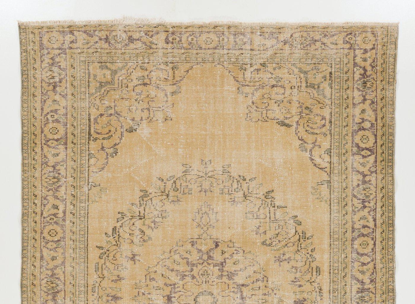 Vintage hand-knotted Turkish area rug from the 1960s with distressed wool pile on cotton foundation. It has a central medallion and a floral wreath around it as well as curvilinear corner pieces and a floral border, all in purplish brown against a