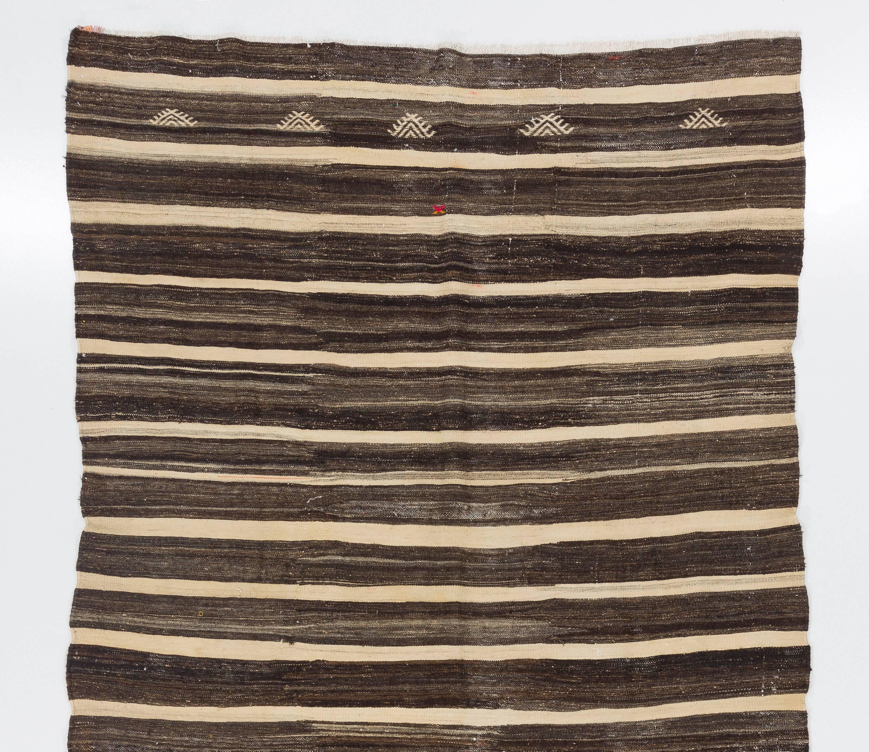 A vintage striped Anatolian Kilim made of natural un-dyed wool, featuring beautifully abrashed tones of cream and brown. Measures: 6.8 x 11.2 ft.
A fitting accompaniment to modern and Minimalist interiors in well preserved condition.
Sturdy and