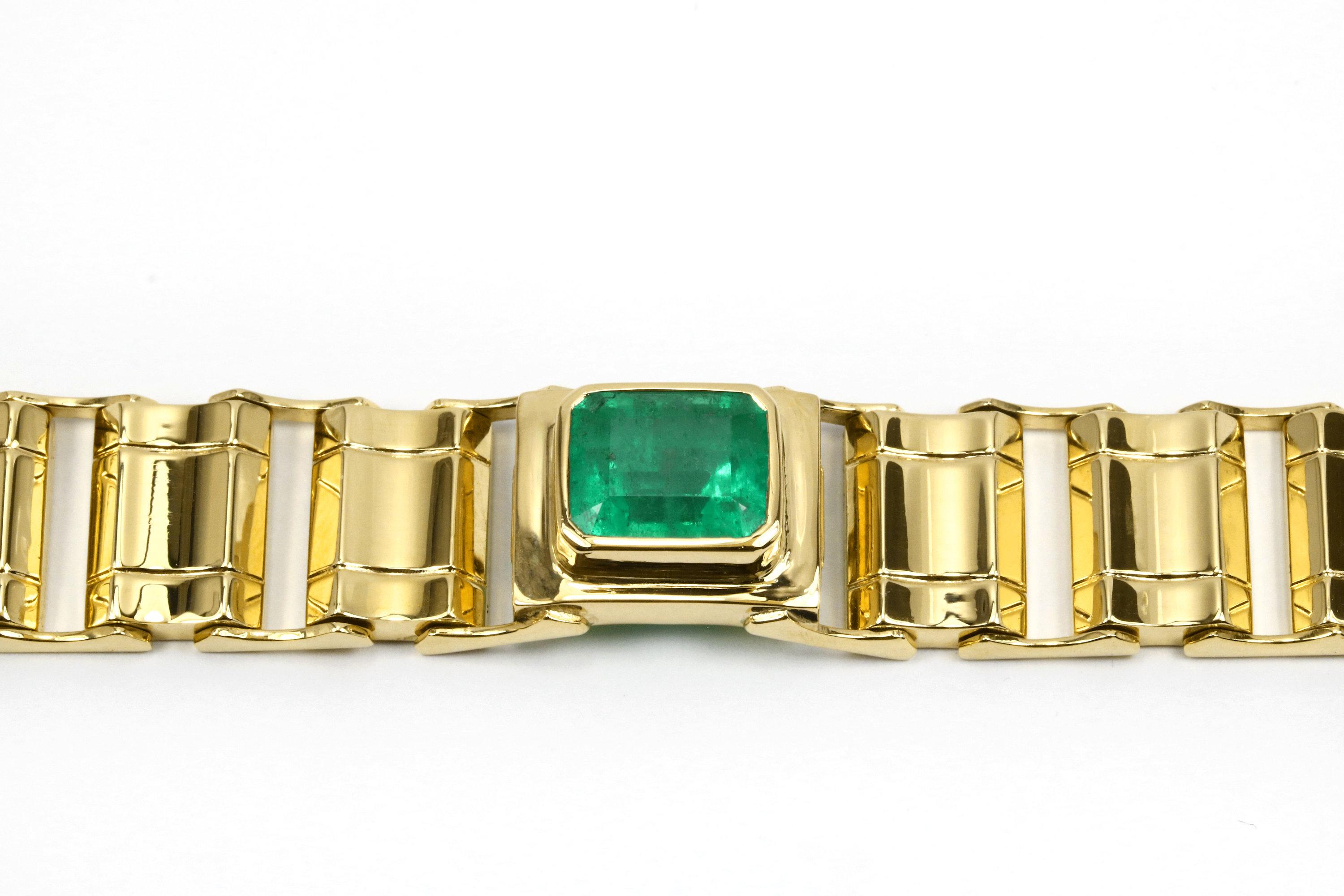 Elegantly showcased is a gold solitaire bracelet with a beautiful 6.90ct, genuine Colombian emerald cut. In its center, elongated rich green emerald is a bezel set horizontally in 14K yellow gold, a mesmerizing focal point. Golden curved links