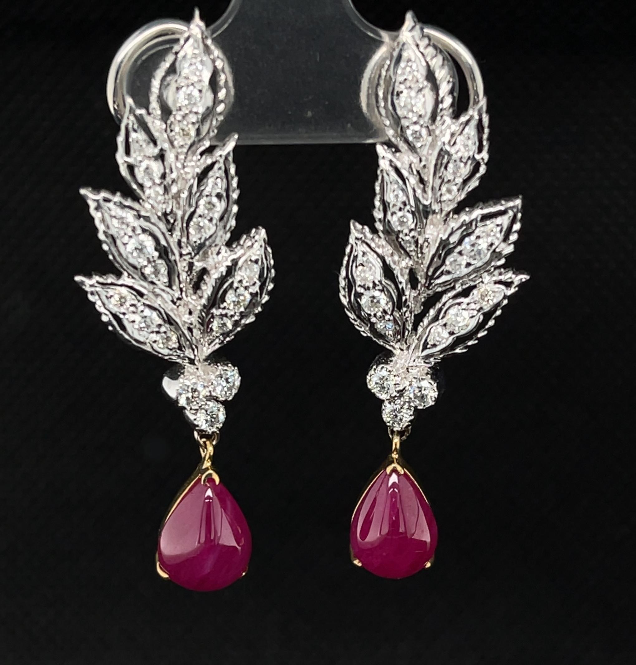 These earrings will make you feel like royalty dripping in fine rubies and diamonds! Two pear-shaped pinkish-red ruby cabochons from Burma are suspended from ornate diamond-set plumes. The plume shaped earring tops are pave-set with sparkly round