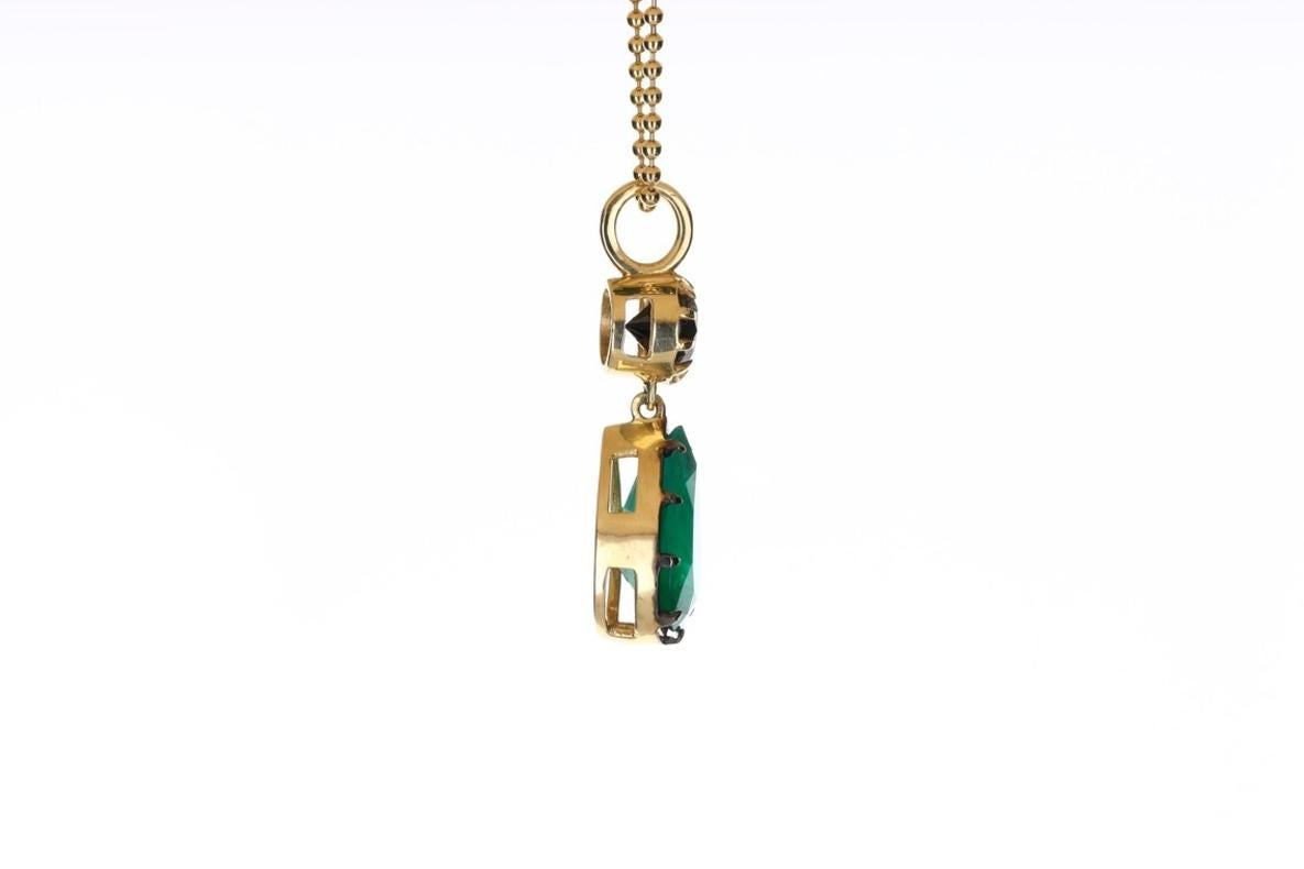 Featured here is a 6.91tcw stunning, Georgian-styled emerald pendant in 18K yellow gold. Displayed in the center is a deep green emerald with very good eye clarity, accented by a 9 prong Georgian setting and an oxidized black rim. A 1.60-carat black