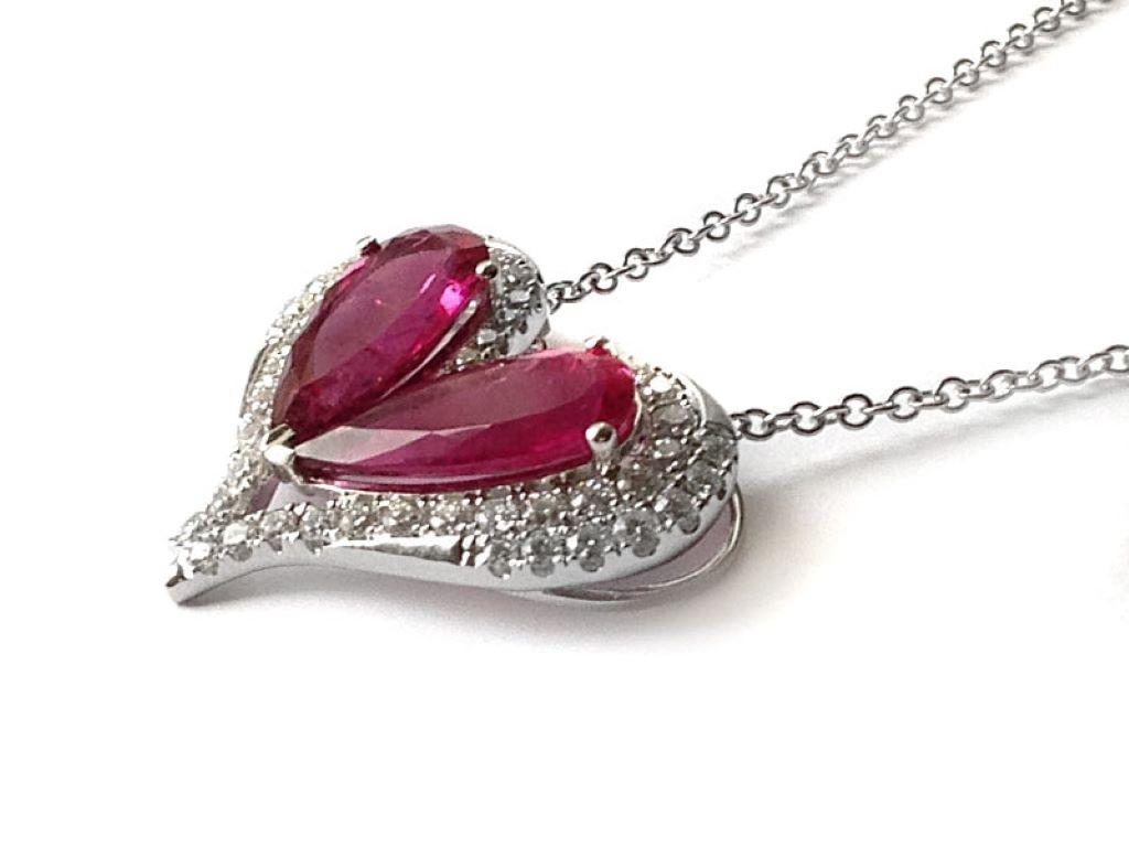 Showing off two impeccably matched pear cut Rubellites each surrounded by a diamond halo, this pendant will easily dazzle her neckline. Bursting with rich color, with a total of 6.93 carats, the fuchsia pink from the gems is brought to life with the