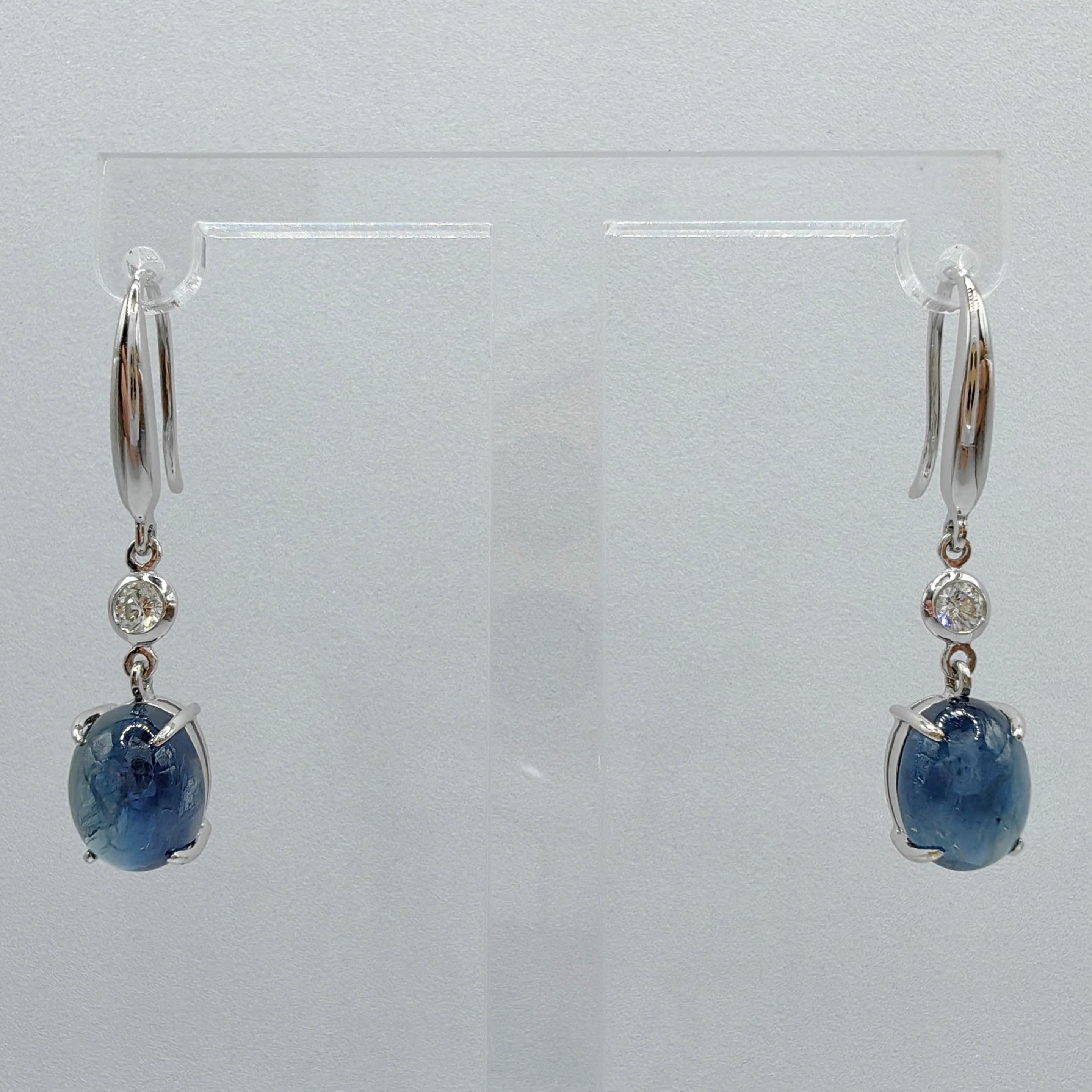 Introducing our exquisite 6.94ct Cabochon Blue Sapphire Diamond Dangling Earrings, where the captivating beauty of blue sapphires and brilliant diamonds takes center stage. 

At the heart of these earrings are two mesmerizing cabochon blue