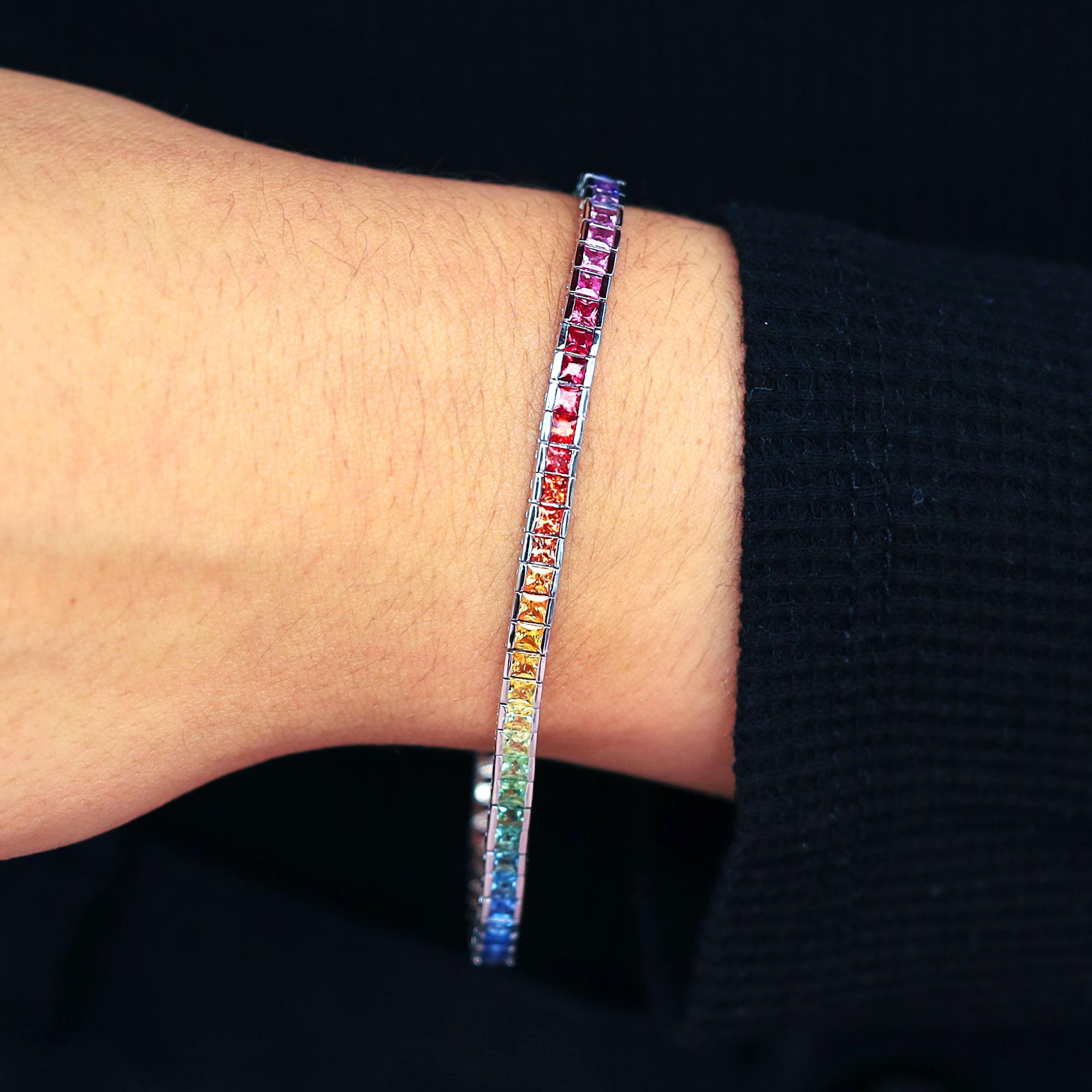 A modern, playful twist on the classic line bracelet. 66 princess cut fancy multi-color sapphires with vivid, bright gradient colors of the rainbow grace this stunning tennis bracelet. A great stacking piece, but also a statement on its own,