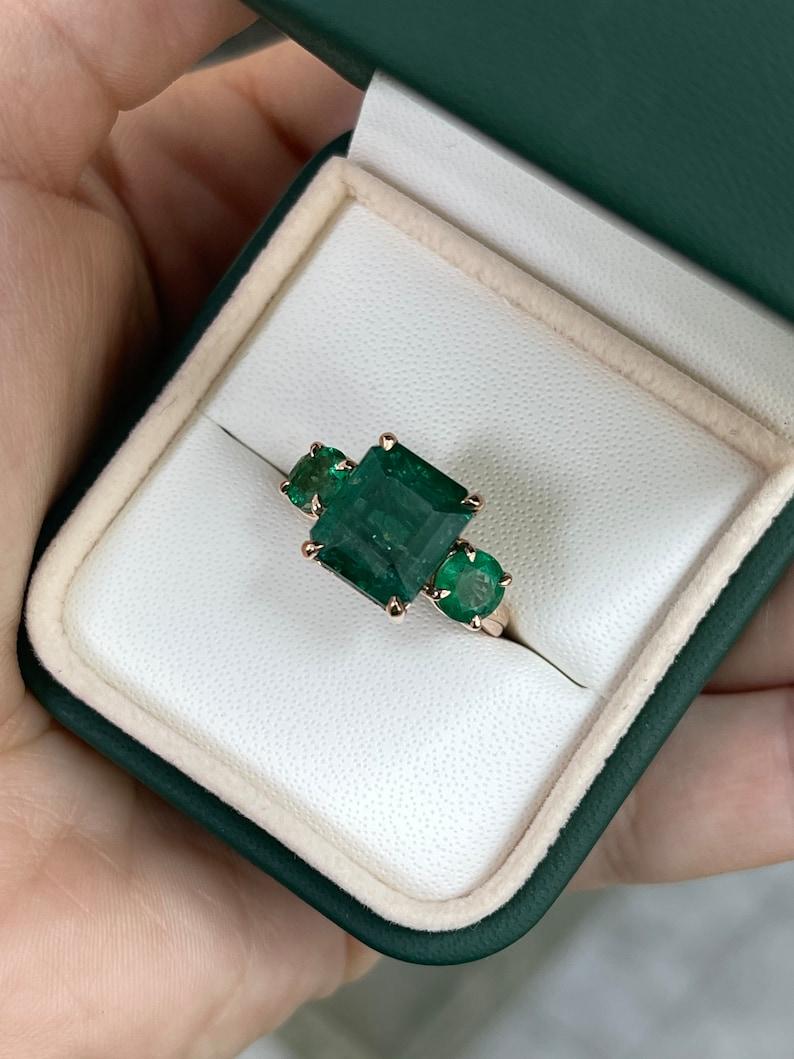 Modern 6.98tcw 14K Emerald Cut & Round Emerald Trilogy Ring - Deep Green 585 Rose Gold For Sale