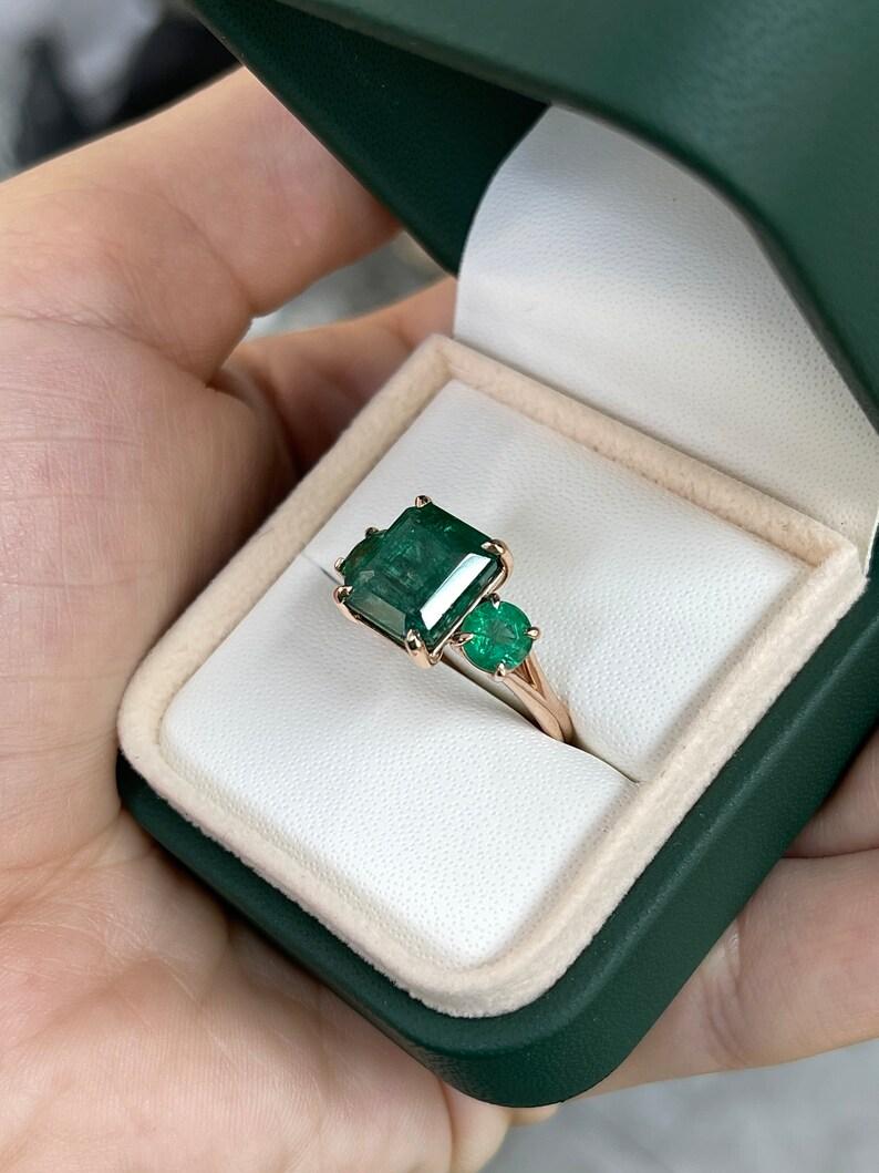 6.98tcw 14K Emerald Cut & Round Emerald Trilogy Ring - Deep Green 585 Rose Gold In New Condition For Sale In Jupiter, FL