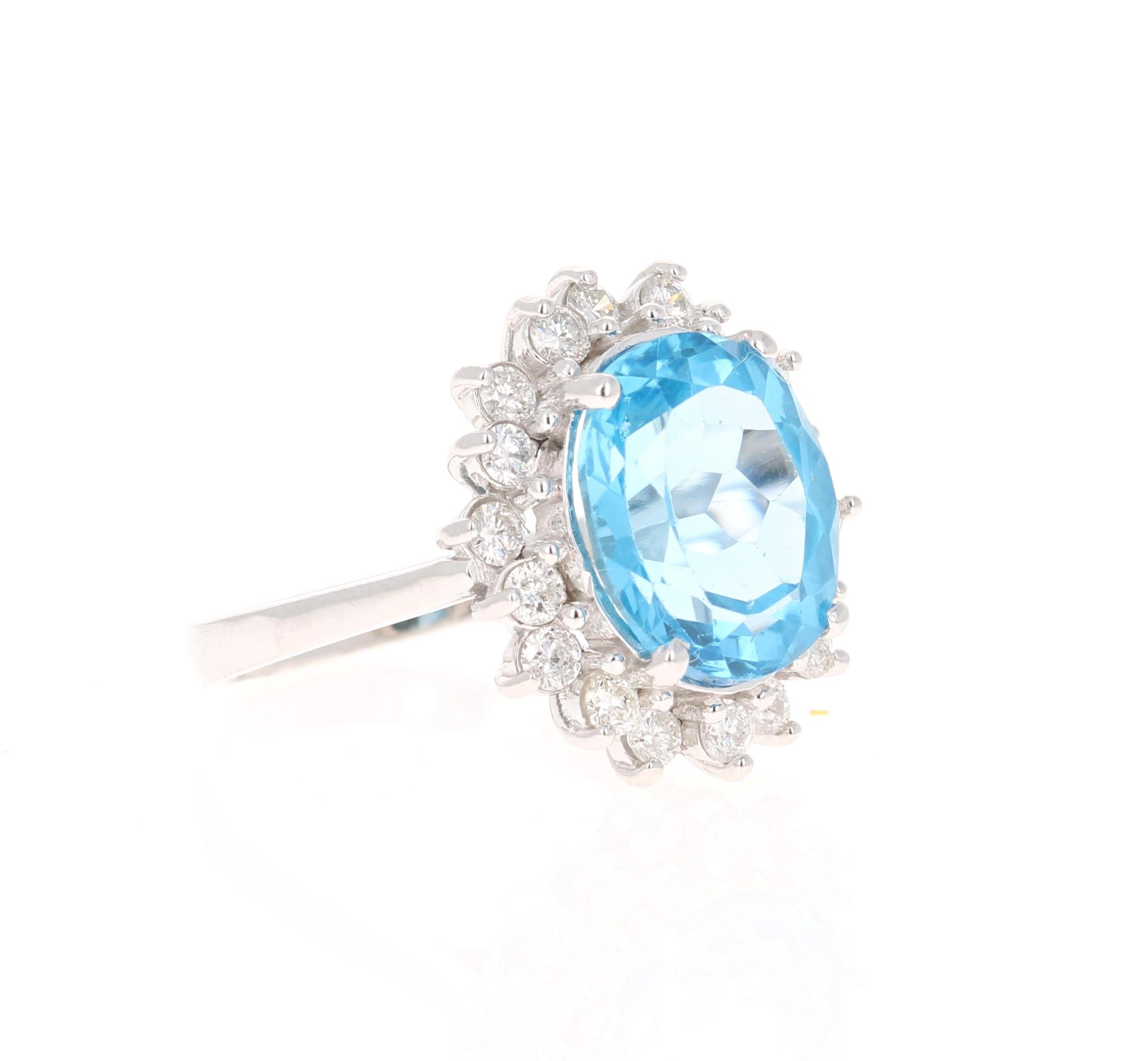 This stunning statement ring has a large Oval Cut Blue Topaz that weighs 6.28 Carats. 
It is surrounded by a simple halo of 18 Round Cut Diamonds that weigh 0.71 Carats. 

It is crafted in 14 Karat White Gold and weighs approximately 4.6 grams.