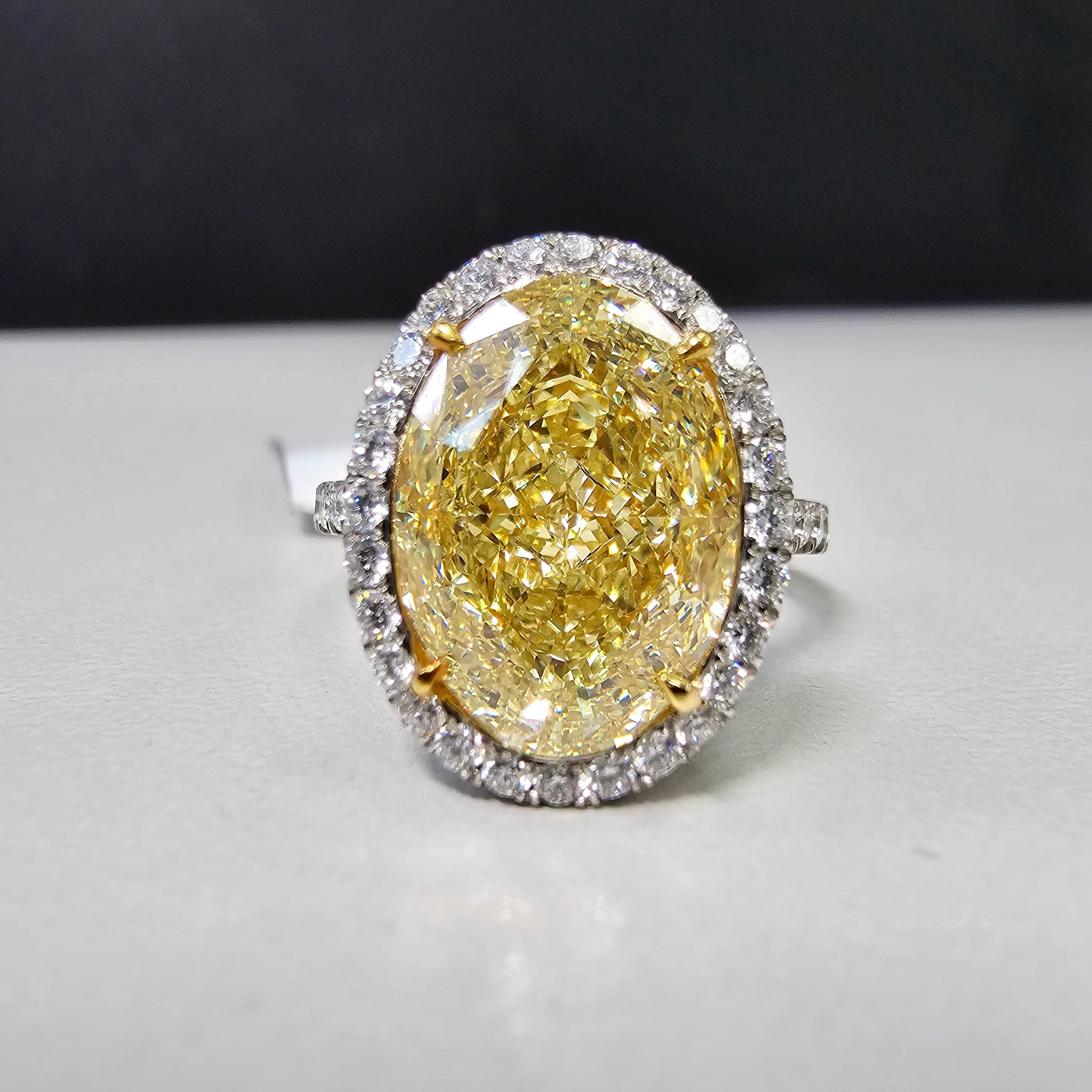 This 6 Carat Fancy Light Yellow Oval Diamond Ring is a beautiful blend of craftsmanship and rarity. The center stone, a GIA-certified Fancy Light Yellow diamond, boasts a VS2 clarity, ensuring eye-catching brilliance. Surrounding the oval-cut center