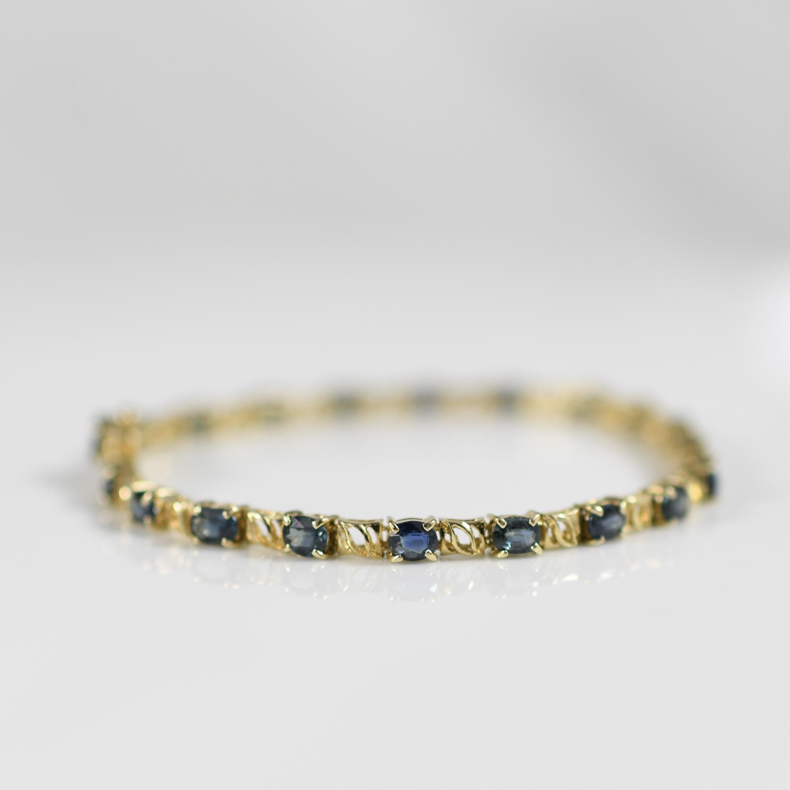 Elevate your wrist with luxurious sophistication wearing this 14k yellow gold bracelet adorned with 6 carats total weight of natural blue sapphire oval gemstones. Each sapphire radiates a deep, captivating blue hue, carefully set to maximize