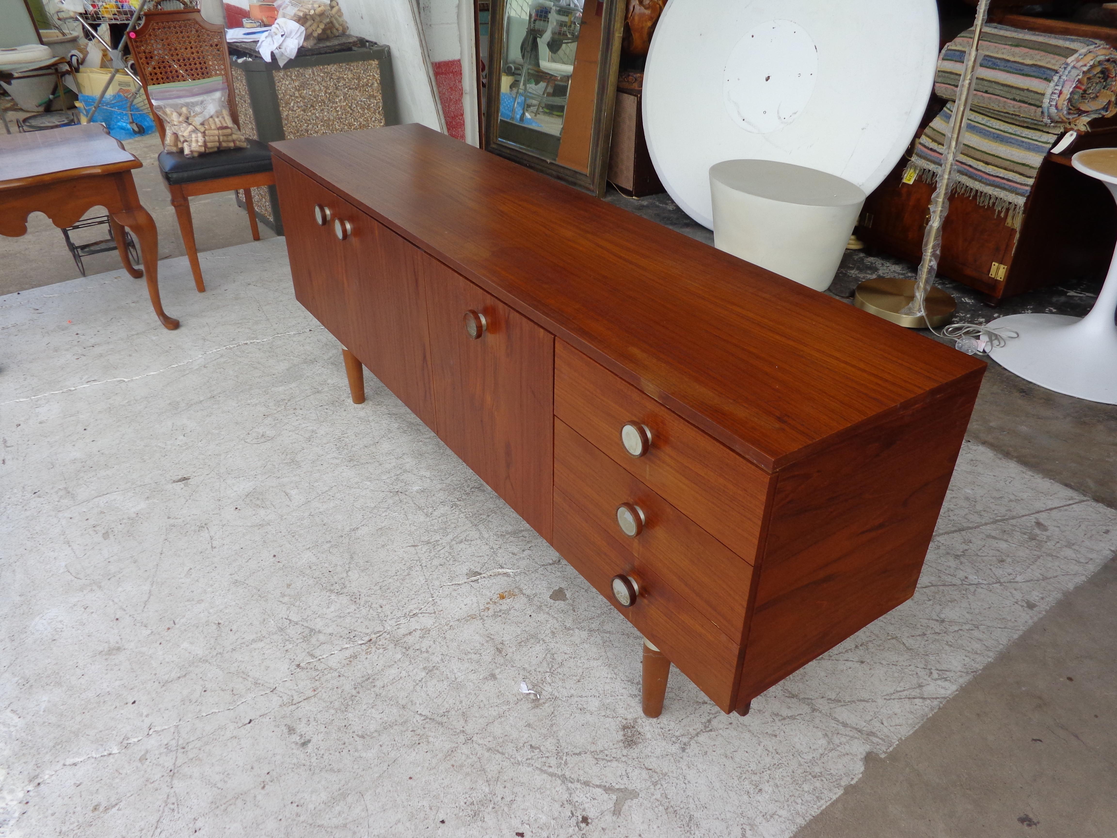 Mid century teak dresser

Mid-Century Modern credenza sideboard, English, circa 1960s. Flamed teak with fitted interior for loads of storage, including silverware drawer, with aluminum pulls and leg wraps. Measure: 6Ft.
 