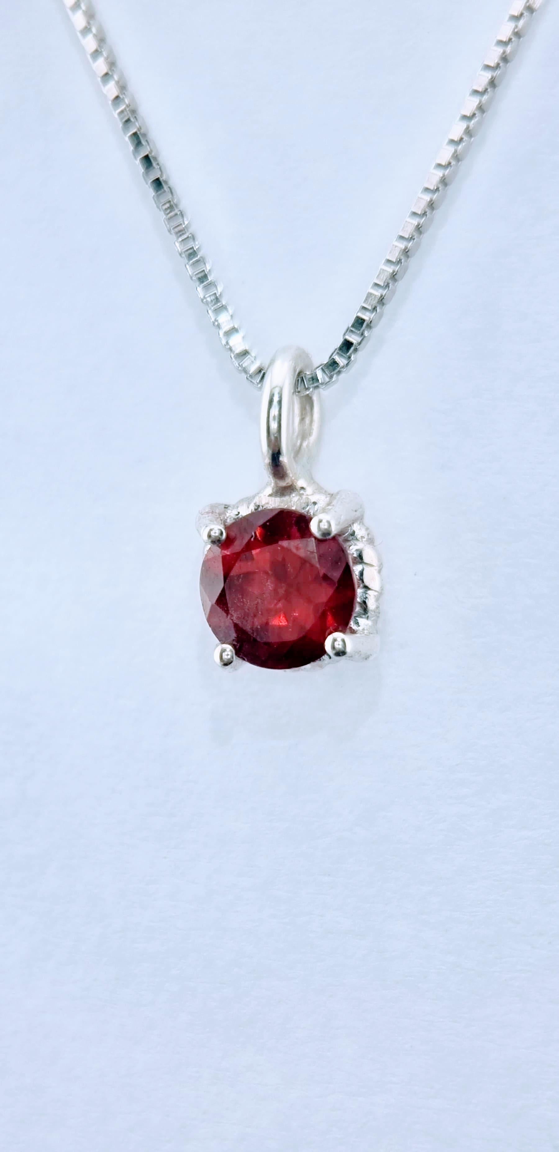 

Elegant dans sa simplicité, ce pendentif délicat présente un grenat naturel rond de 6 mm de diamètre serti dans une monture torsadée à quatre branches. La pierre précieuse d'un rouge profond, célèbre pour son allure intemporelle et sa richesse