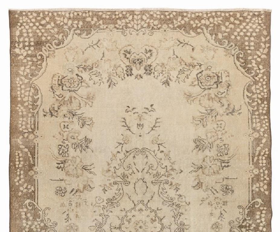 This is a hand-knotted vintage Turkish area rug. The rug features a floral medallion design in a field decorated with floral motifs. It has low distressed wool pile on cotton foundation, is in very good condition, sturdy and clean as a brand new