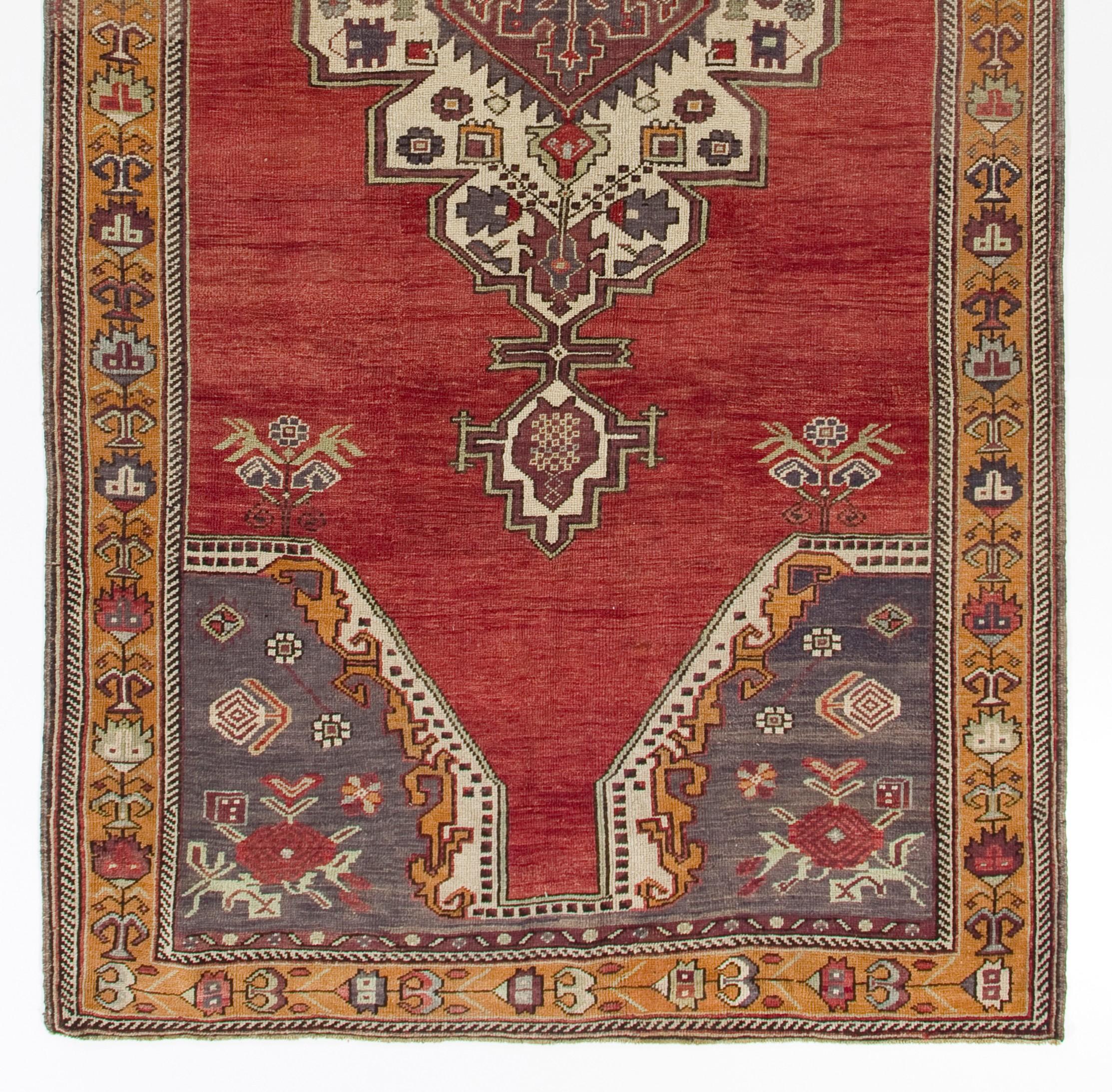 A lovely vintage hand-knotted Central Turkish rug with a design that features classical themes with a tribal aesthetic, that is more rectilinear and geometric with saturated, deep colors of red, indigo and marigold as well as cream. Measures: 5.9 x