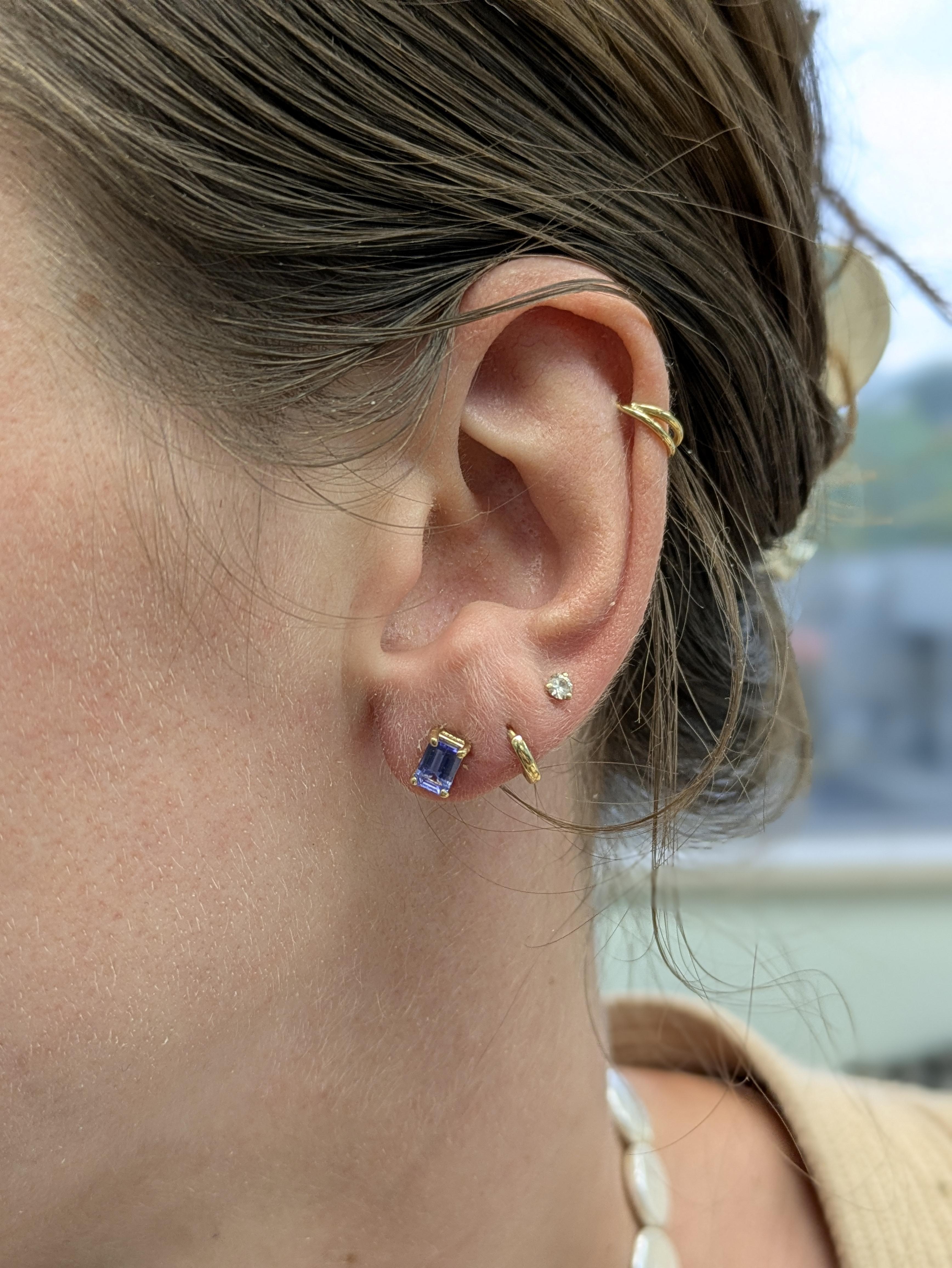 Queste borchie di tanzanite uniscono un design senza tempo a un significato sincero. Incastonate nell'oro giallo 14k, le pietre con taglio a smeraldo da 6x4 mm risplendono di una serena tonalità viola. Delicati ma di grande effetto, sono un
