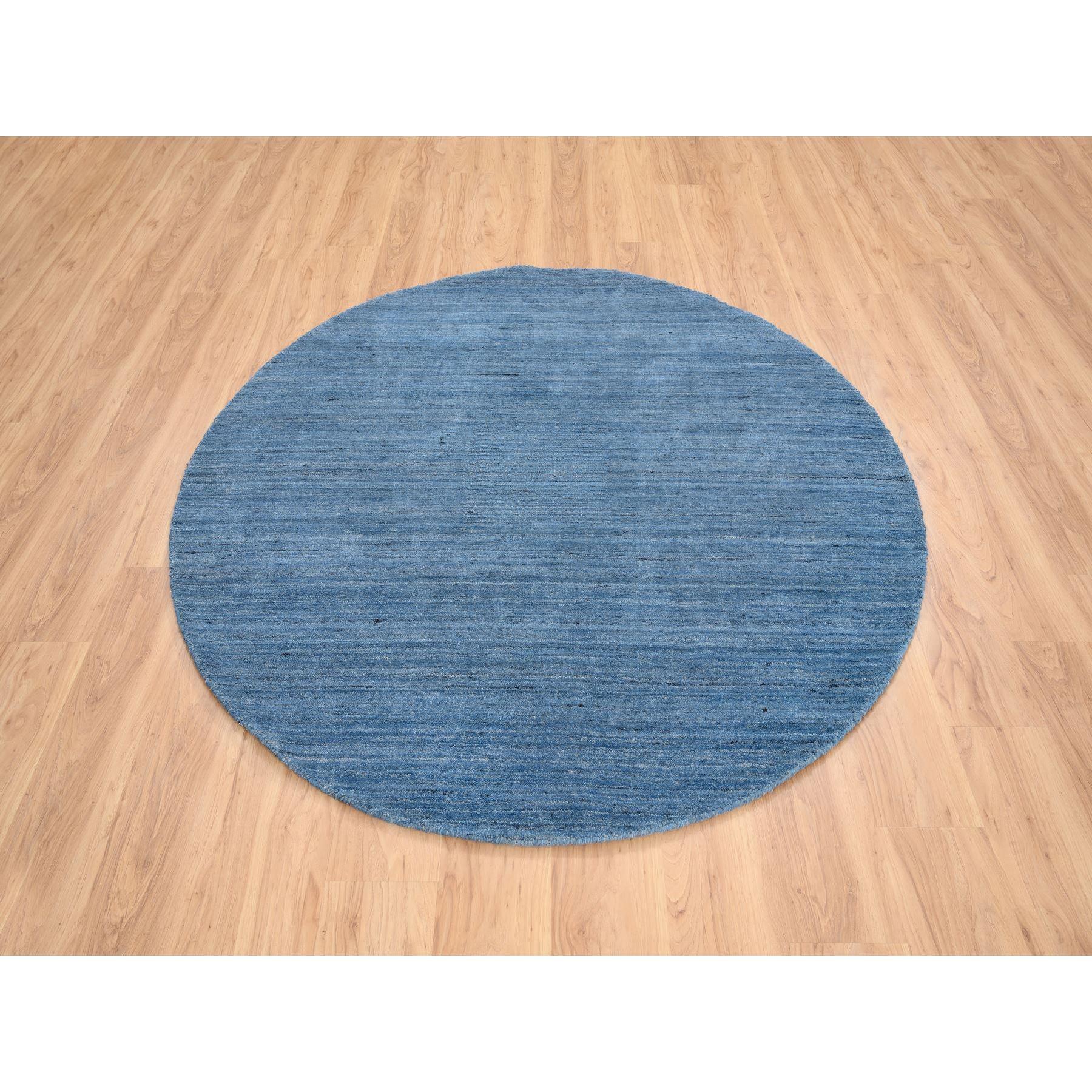 Il s'agit d'un véritable tapis d'Orient, unique en son genre, bleu denim, en laine douce, tissé à la main, au design moderne, de forme ronde. Il a été tissé pendant des mois et des mois selon des techniques artisanales séculaires par des artisans