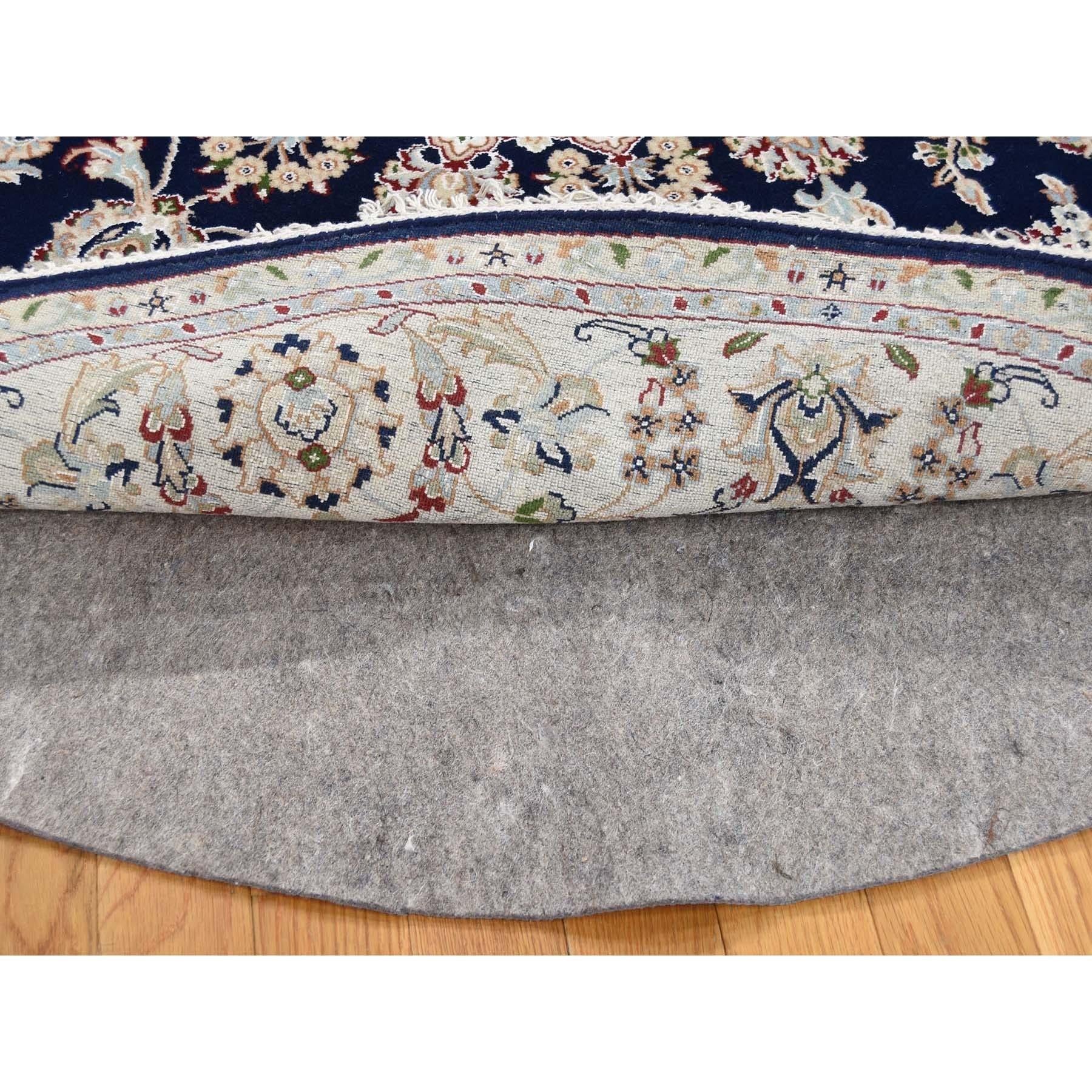 Se trata de una auténtica alfombra oriental redonda anudada a mano de 250 KPSI, de color azul noche con medallón central y diseño floral. Ha sido tejida durante meses y meses con las centenarias técnicas artesanales del tejido persa por