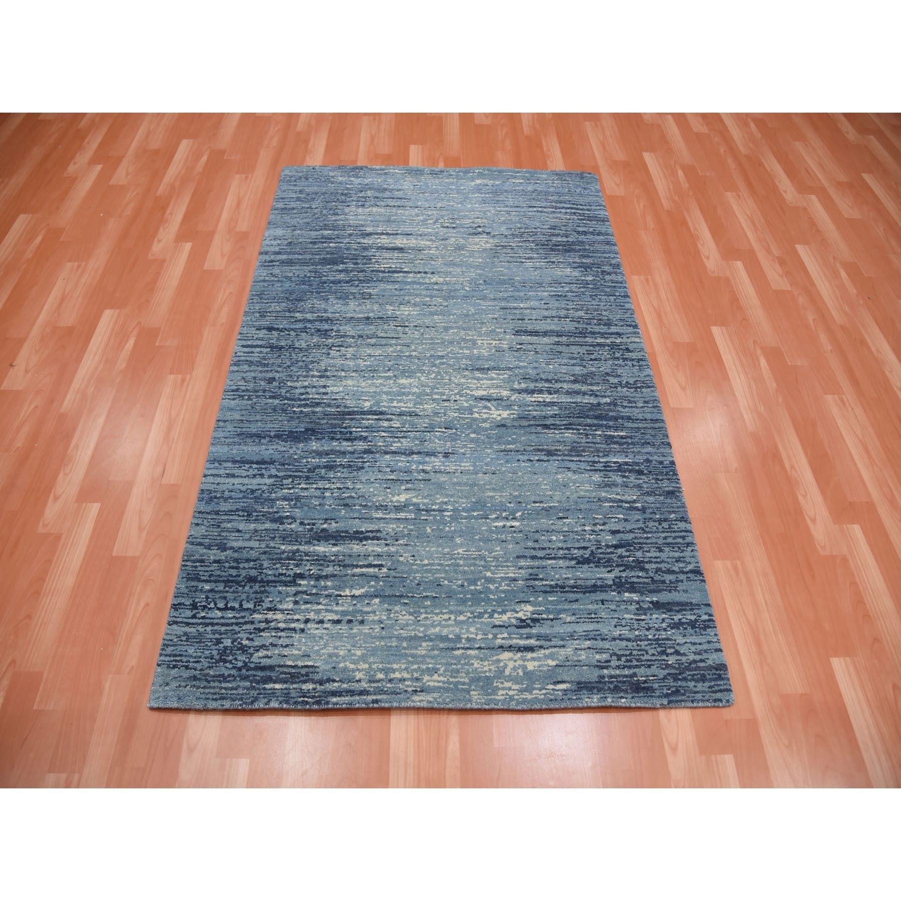 Il s'agit d'un véritable tapis oriental en pure laine nouée à la main, de couleur bleue avec des touches d'ivoire, au design horizontal et ombré. Il a été noué pendant des mois et des mois selon les techniques séculaires du tissage persan par des