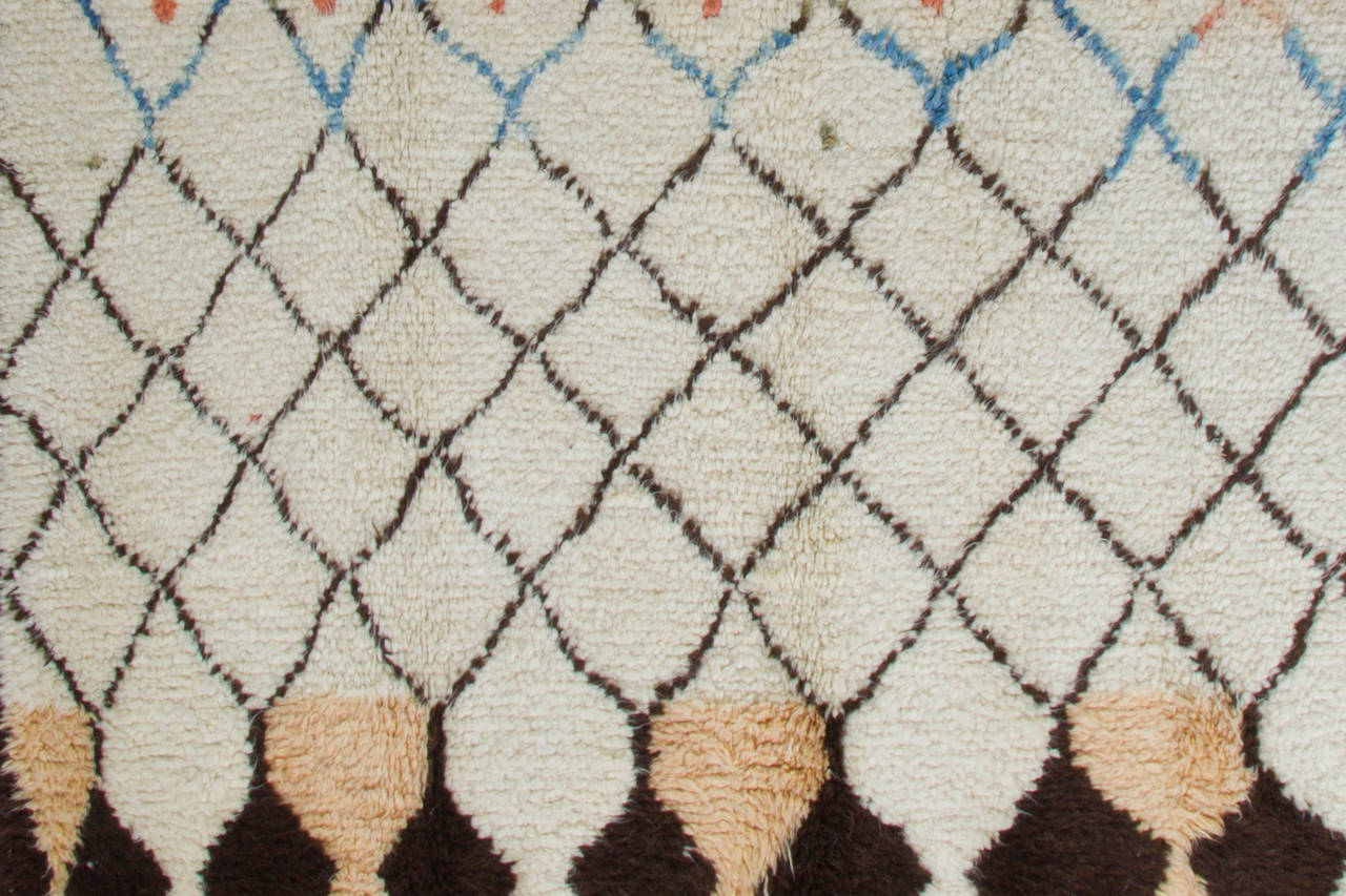 A contemporary hand-knotted Moroccan rug with soft, lustrous sheep's wool pile that is ideal for families with kids and those who seek coziness and comfort with a modern, minimalist aesthetic. The rug features a design of lozenge shaped lattices in