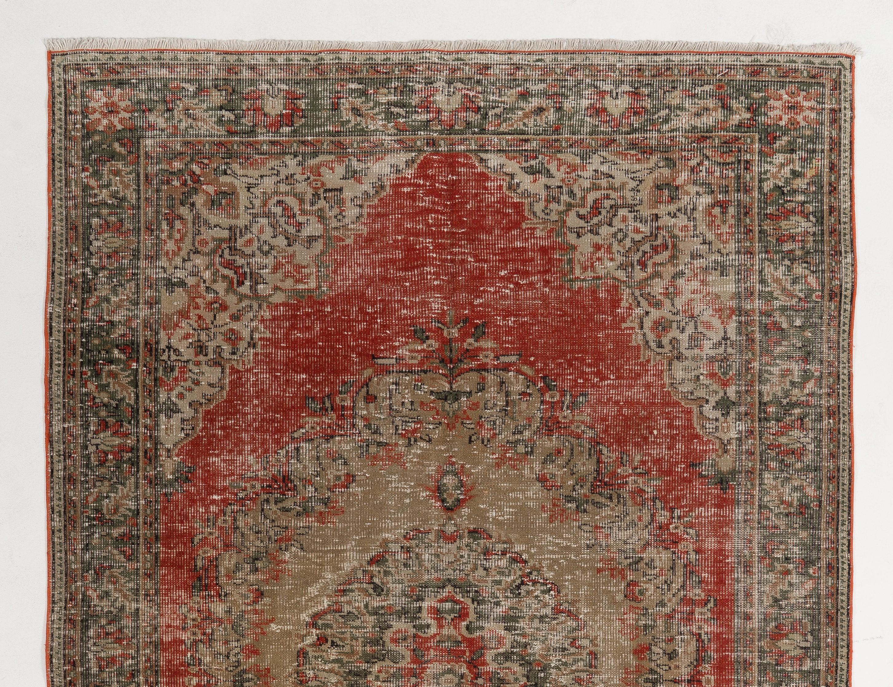 A vintage hand-knotted Turkish rug with a distressed, antiquated looking texture and a medallion design against a bright madder red field, surrounded by spandrels and an outer border filled with well-drawn rosettes, leafy and floral vines in pine