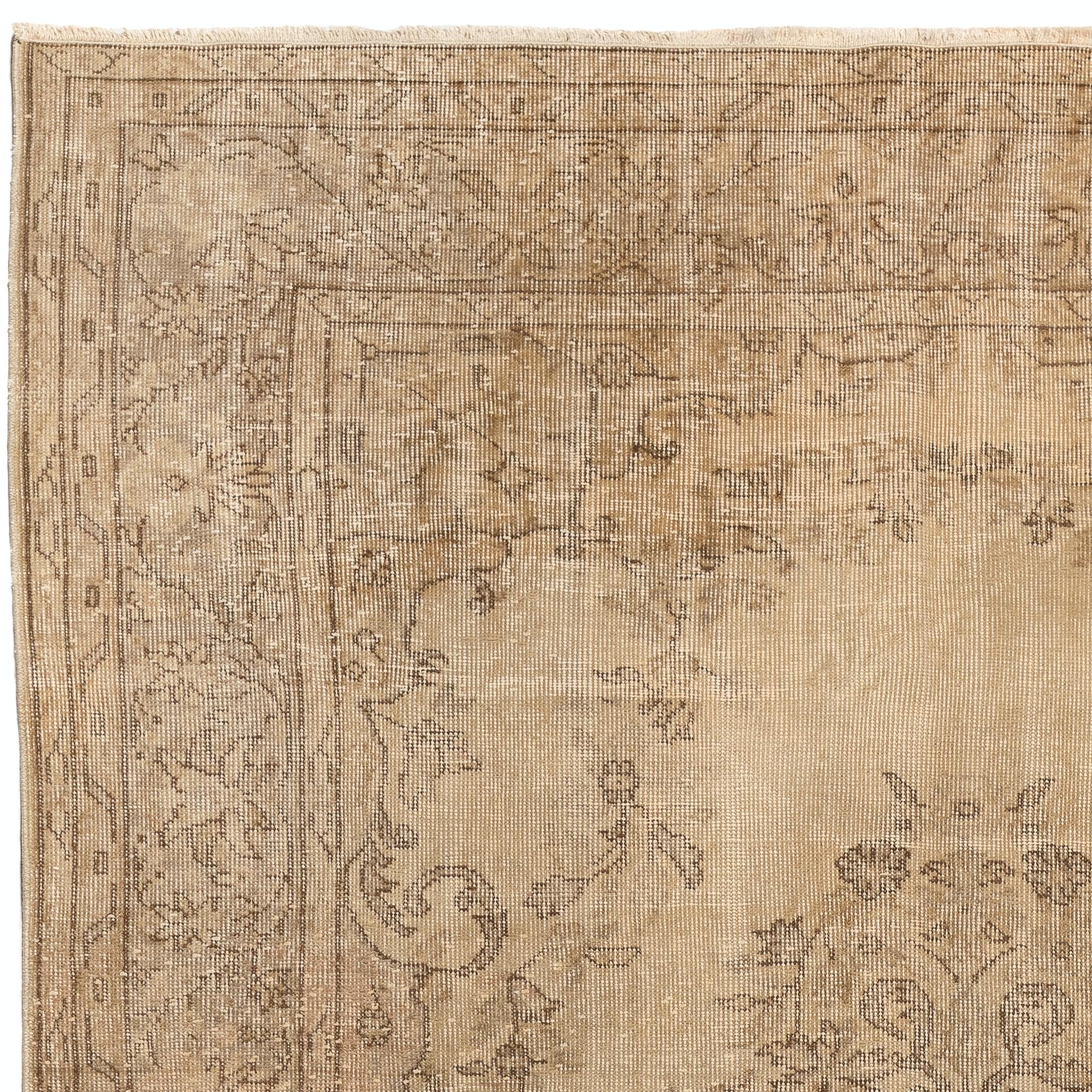 A finely hand-knotted vintage Turkish rug from the 1960s featuring a delicate medallion design decorated all around with lush floral wreaths in brown and taupe gray against a sand beige background. The rug has distressed low wool pile on cotton