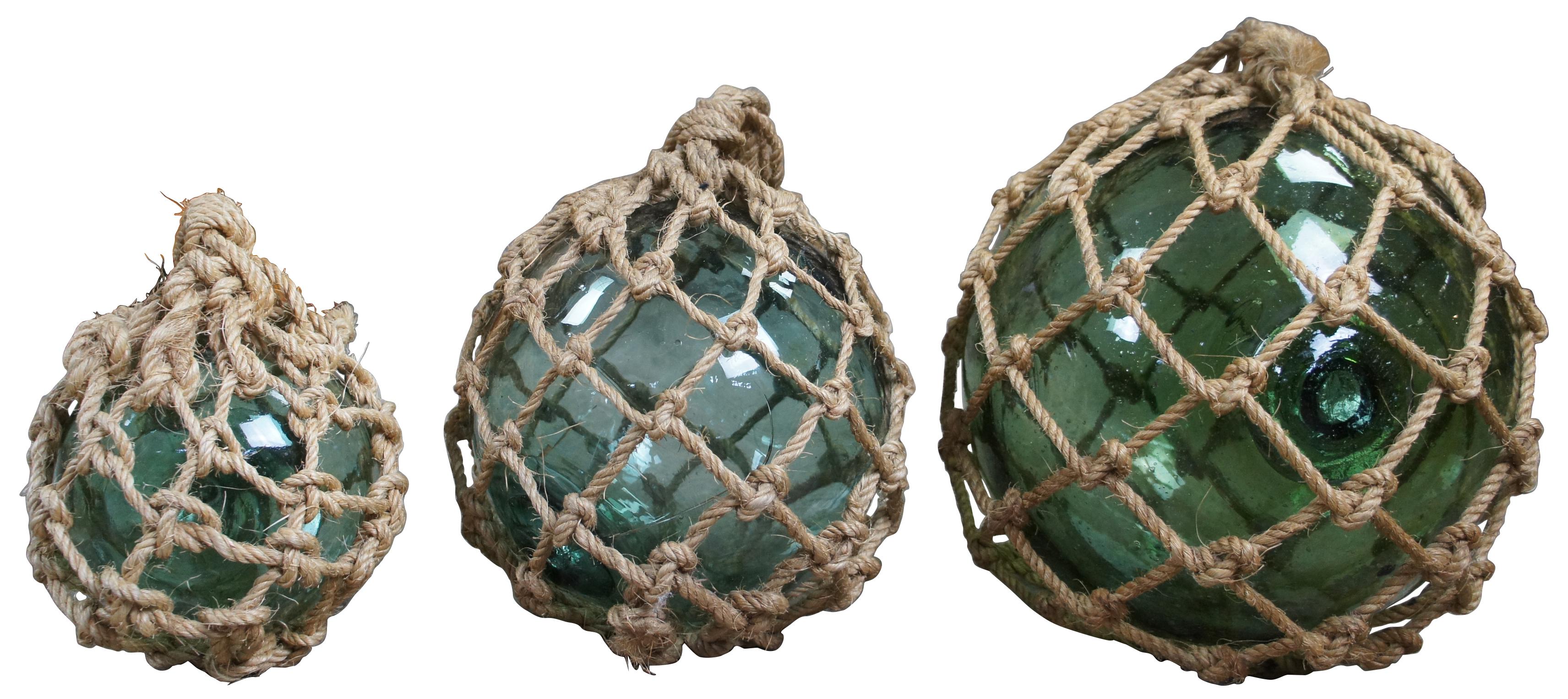 Lot 7 hand blown netted blue Japanese fishing floats. Made from recycled glass bottles and used to buoy a fisherman's net when cast into the water. Feature hand tied knots with hanging loop making them great for use on a dock or displayed in a