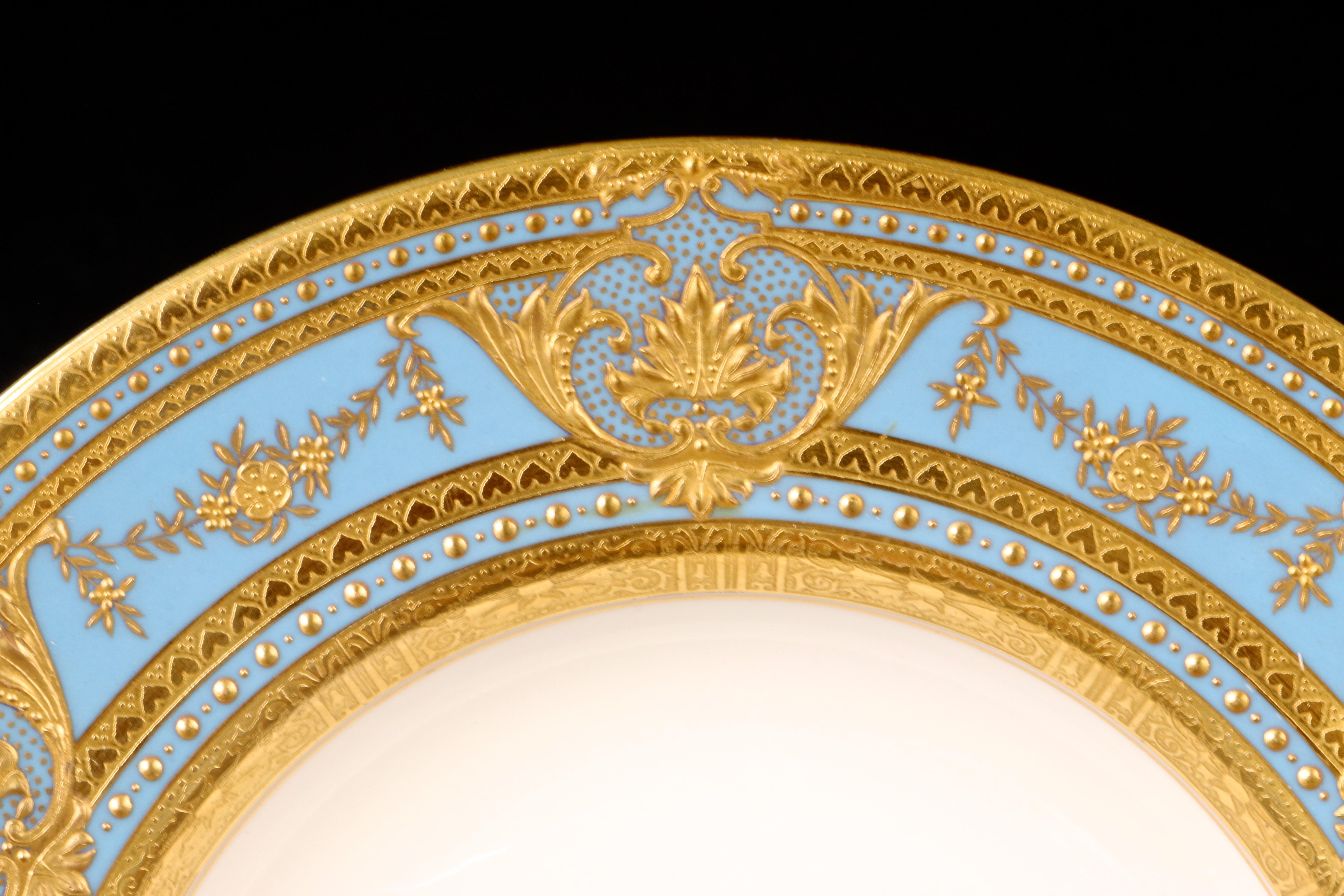Here are 7 Minton, Stoke-on-Trent, Staffordshire, England 22-karat raised-paste gold and blue heavily gilded soup plates. The soup plates feature 6 gilded cartouches composed of a central leaf and foliate, interspersed between the cartouches is a