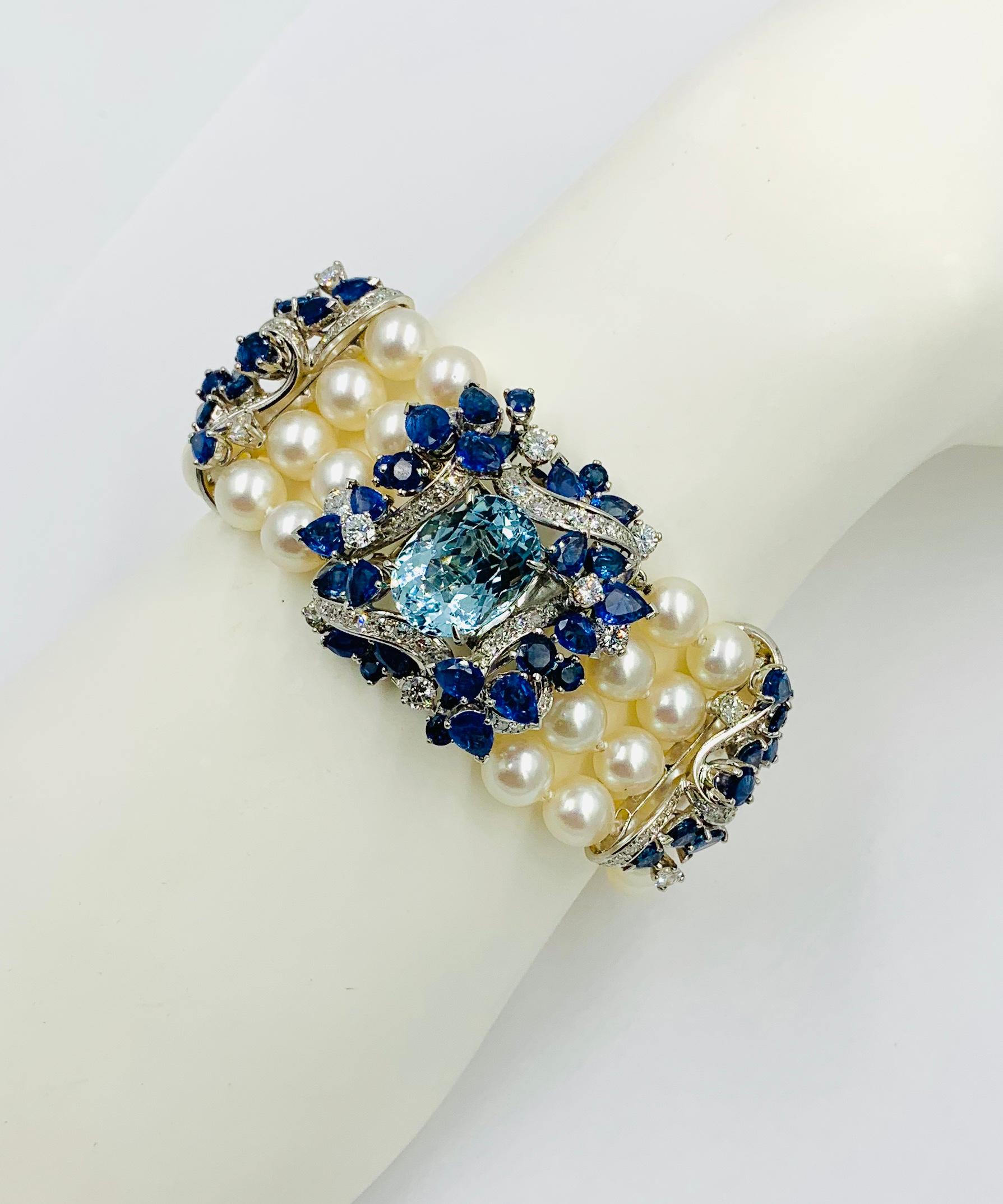 This is a magnificent French statement Four Strand Pearl Bracelet set with a spectacular central 7 Carat Aquamarine.  The Aquamarine is surrounded by 10 Carats of fine blue Sapphires and spectacular white clean Diamonds.  The jewels are set in 18