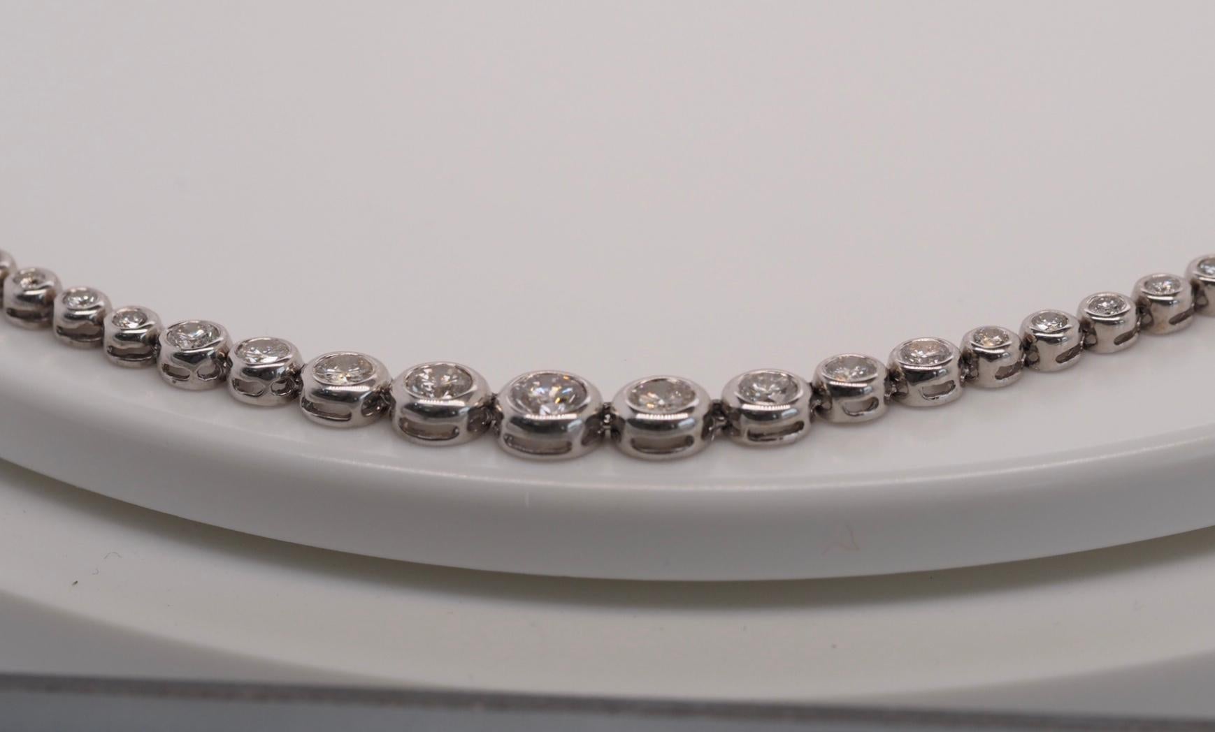 This stunning 14 Karat White Gold Round Brilliant Cut Diamond Tennis Necklace includes 103 individually bezel set diamonds with a total of 7 carats. They taper in size from top to bottom from 1.9mm to a 4.9mm.  The closure is a tongue in groove with
