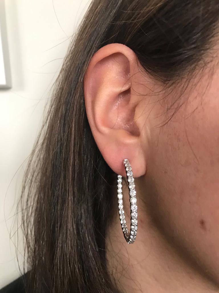 Diamond hoops set in 14K white gold. The total weight is 7 carats. Earrings are set with 52 stones each weighing approximately 0.15 carats. The color and clarity of the diamonds are G-H, SI1-SI2. The hoops are measured at 1.5 inch diameter. 