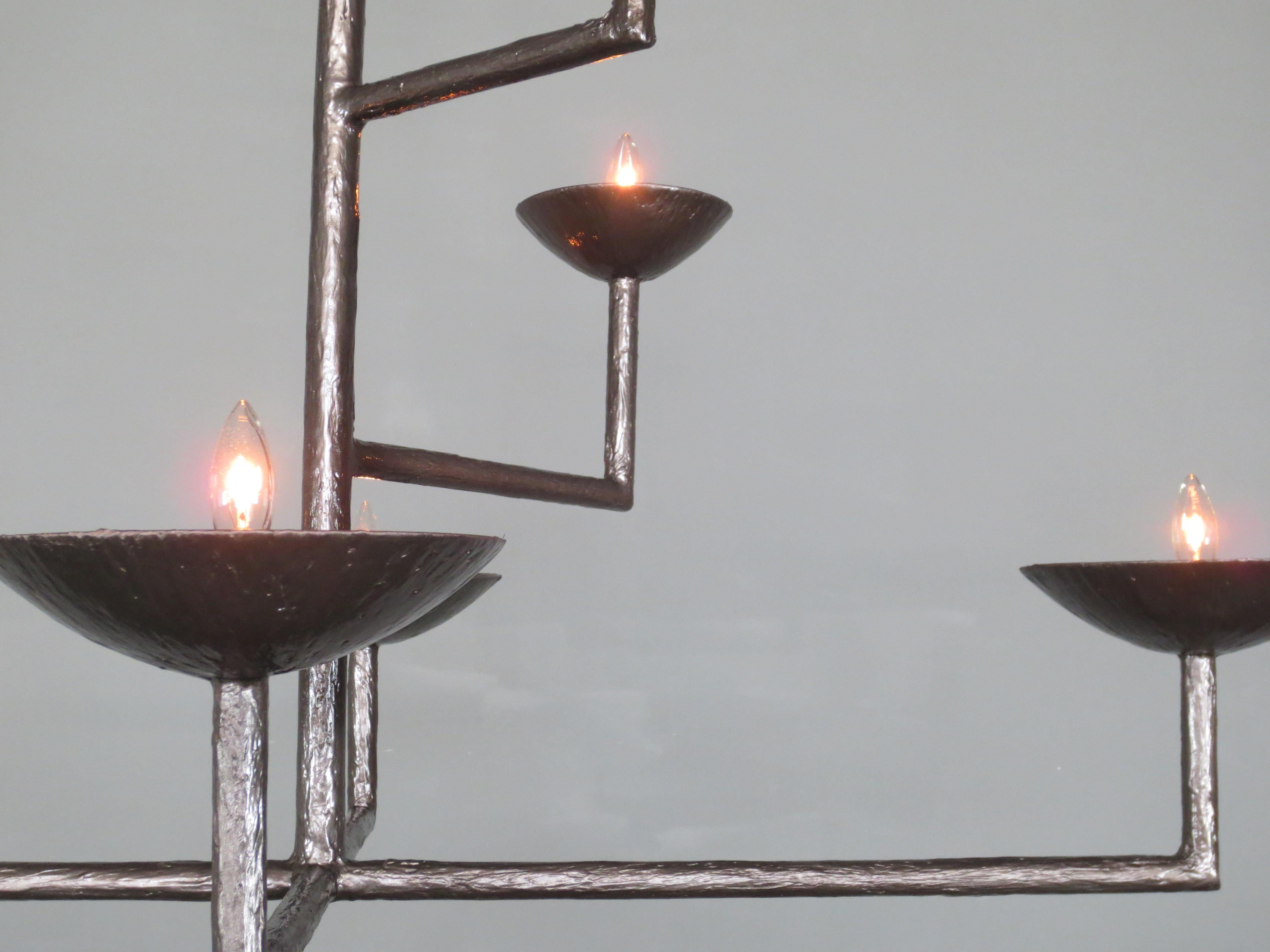 lustre en plâtre de 7 tasses en finition bronze avec demi-boule et chaîne par Tracey Garet de Apsara Interior Design
Les 7 coupes de ce lustre se trouvent à différents niveaux. Chaque tasse contient une lumière de candélabre. La pièce présentée est