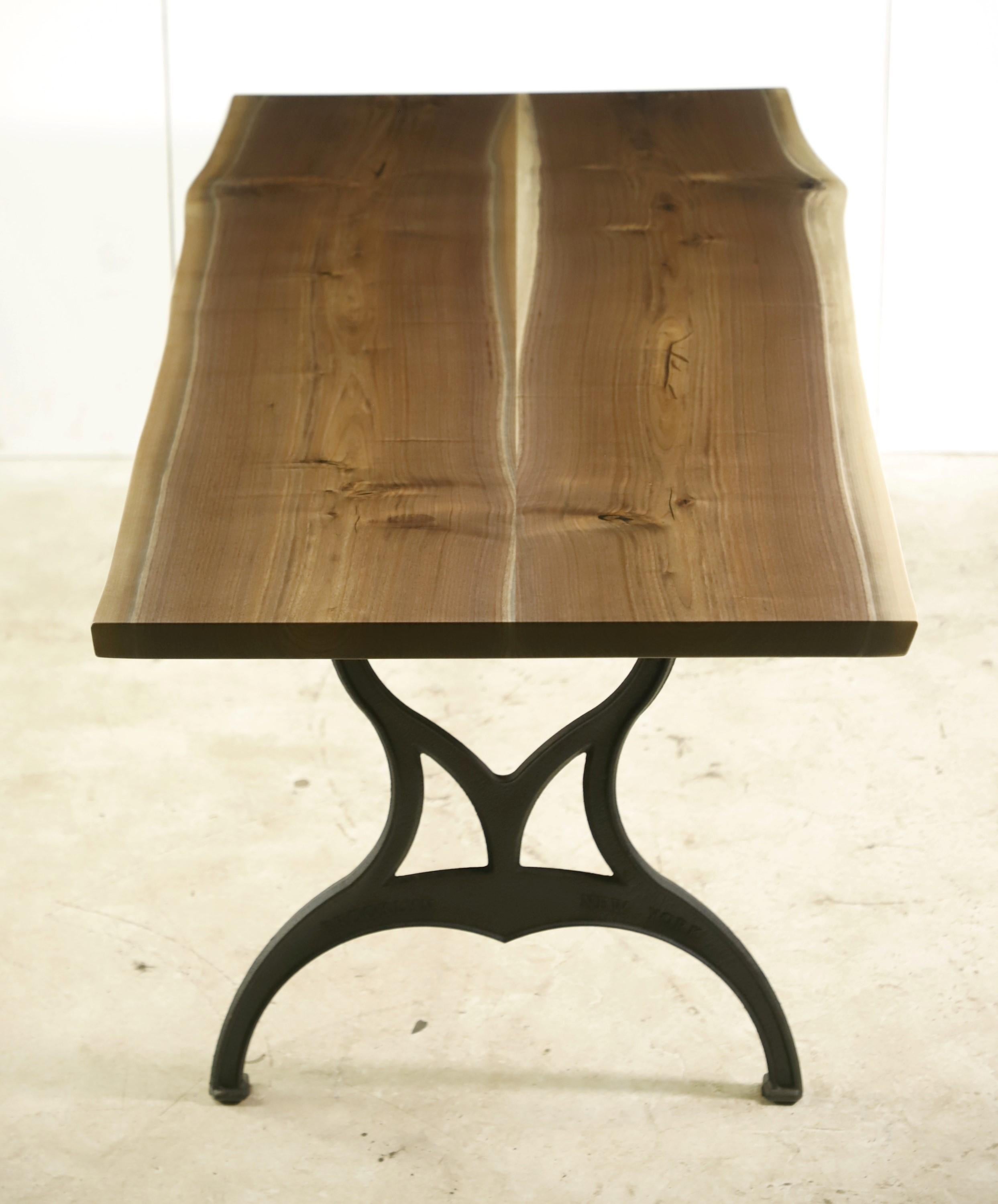 This live edge table features a two slab solid walnut top with a smooth satin finish paired with cast iron Brooklyn legs. This table is ready to ship. Please note, this item is located in our Scranton, PA location.