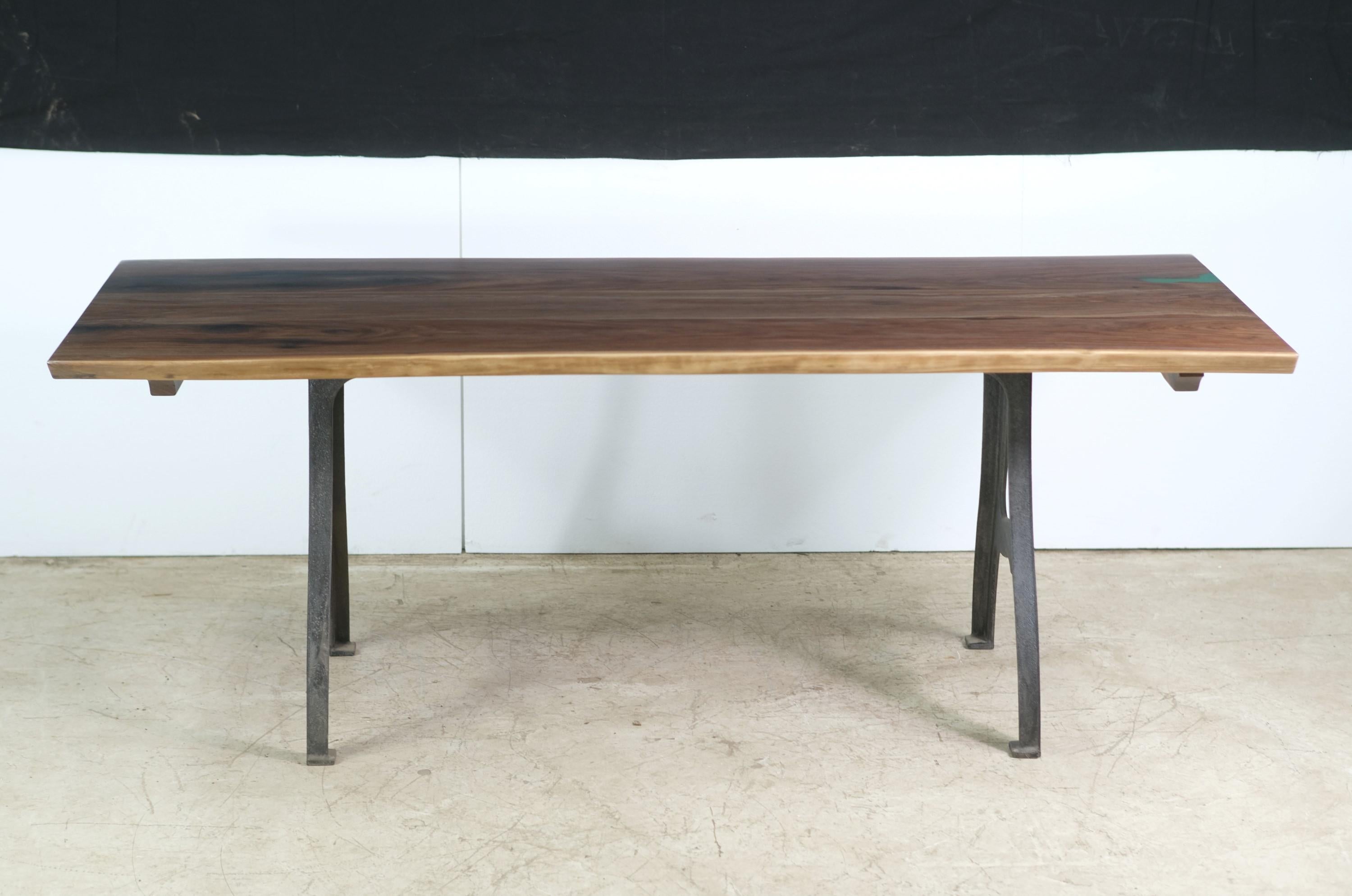 This table features a live edge three slab walnut top with a small and subtle blueish green resin pour paired with New York cast iron legs. This table is ready to ship.  Please note, this item is located in our Scranton, PA location.