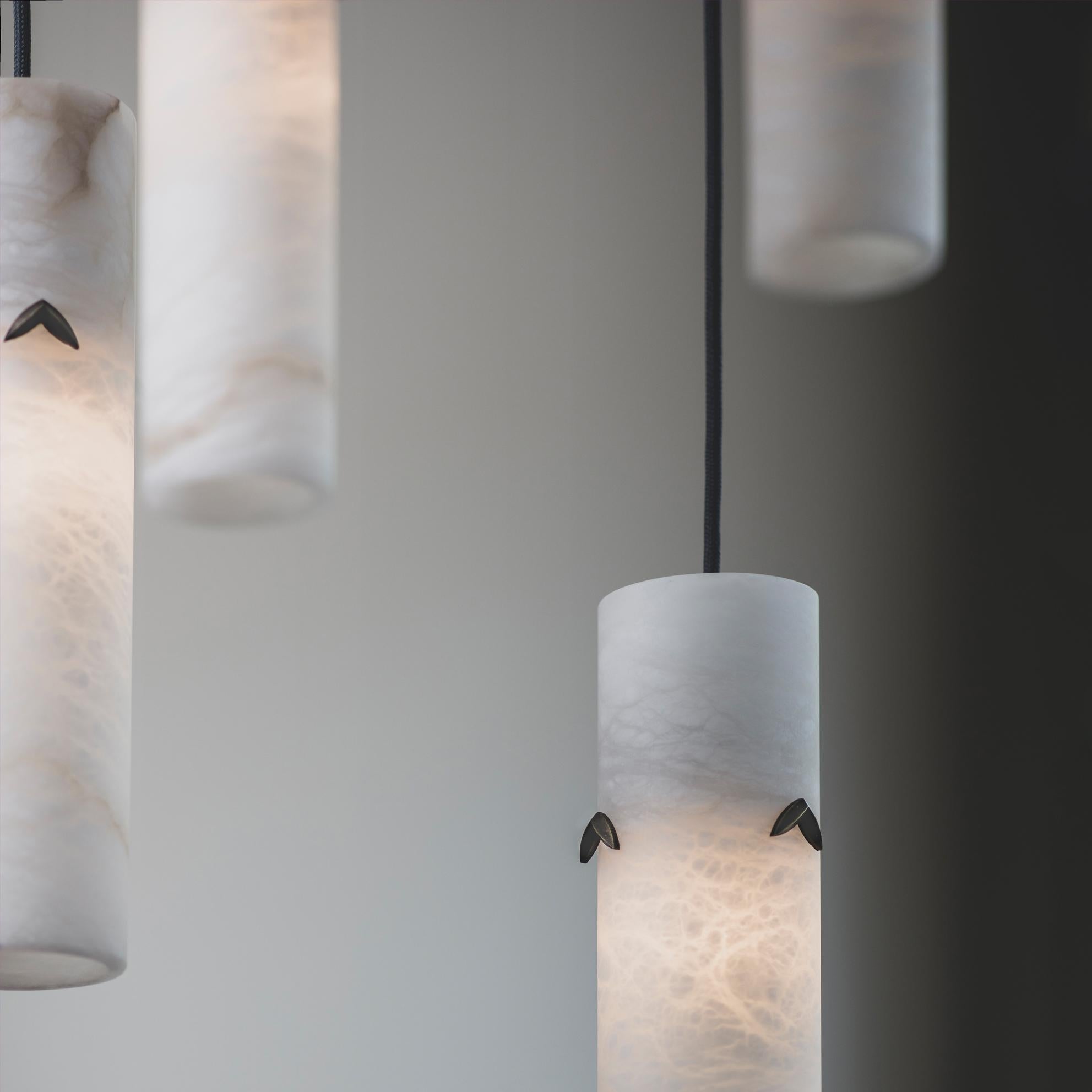 A cluster of pendant lights hewn from solid Alabaster. When lit, the alabaster shade offers a stunning diffuse light and displays a fascinating marbled texture. Each alabaster pendant light shade is adorned with three bronze leaf