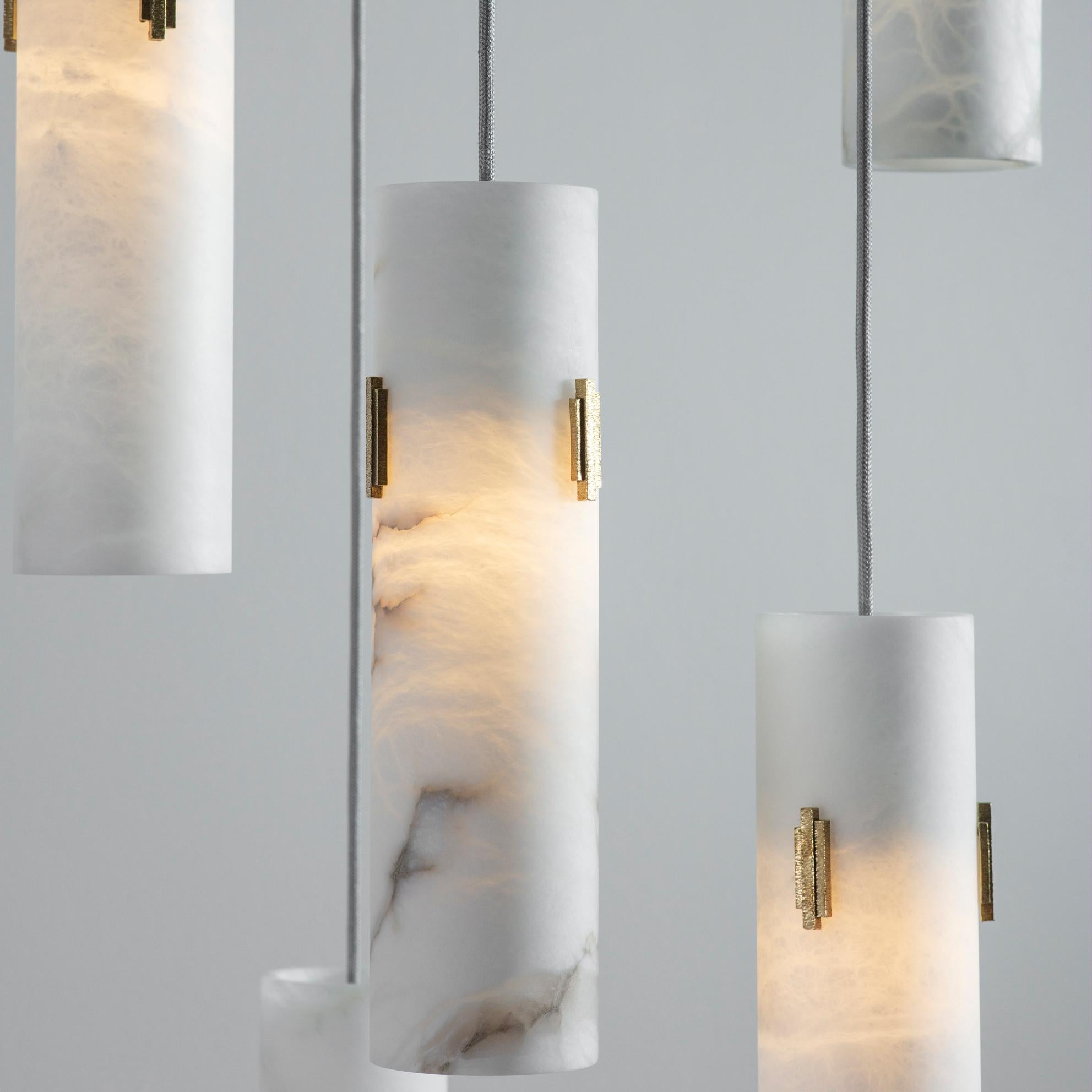 A cluster of pendant lights hewn from solid Alabaster. When lit, the alabaster shade offers a stunning diffuse light and displays a fascinating marbled texture. Each Alabaster Pendant Light shade is adorned with three Antique Brass Deco
