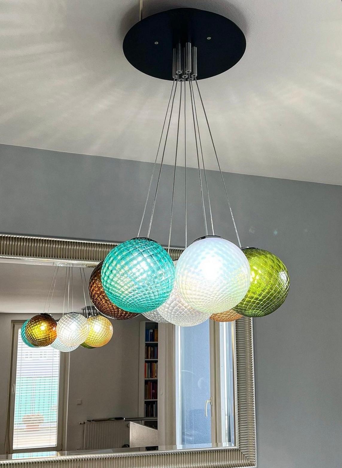 Artistic ceiling chandelier, handcrafted with colored transparent Murano glass spheres. Contemporary, playful, and poetic are some of the adjectives that can be used to describe this chandelier, handmade in our family-owned furnace. This collection