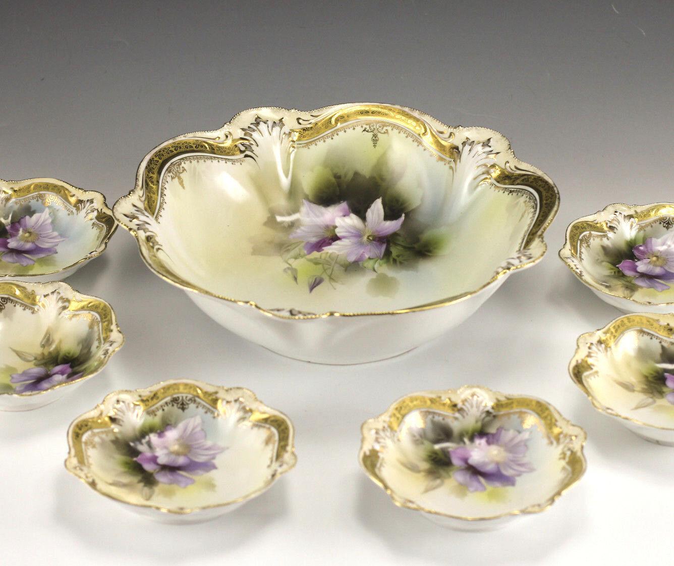 Early 20th Century 7 pc Set Porcelain Berry Serving Bowl with Small Bowls - R S Prussia - Raised or embossed designs hand painted with detailed purple floral design. Gold gilt. Lobed shape with scalloped rims - Red Star mark

Additional