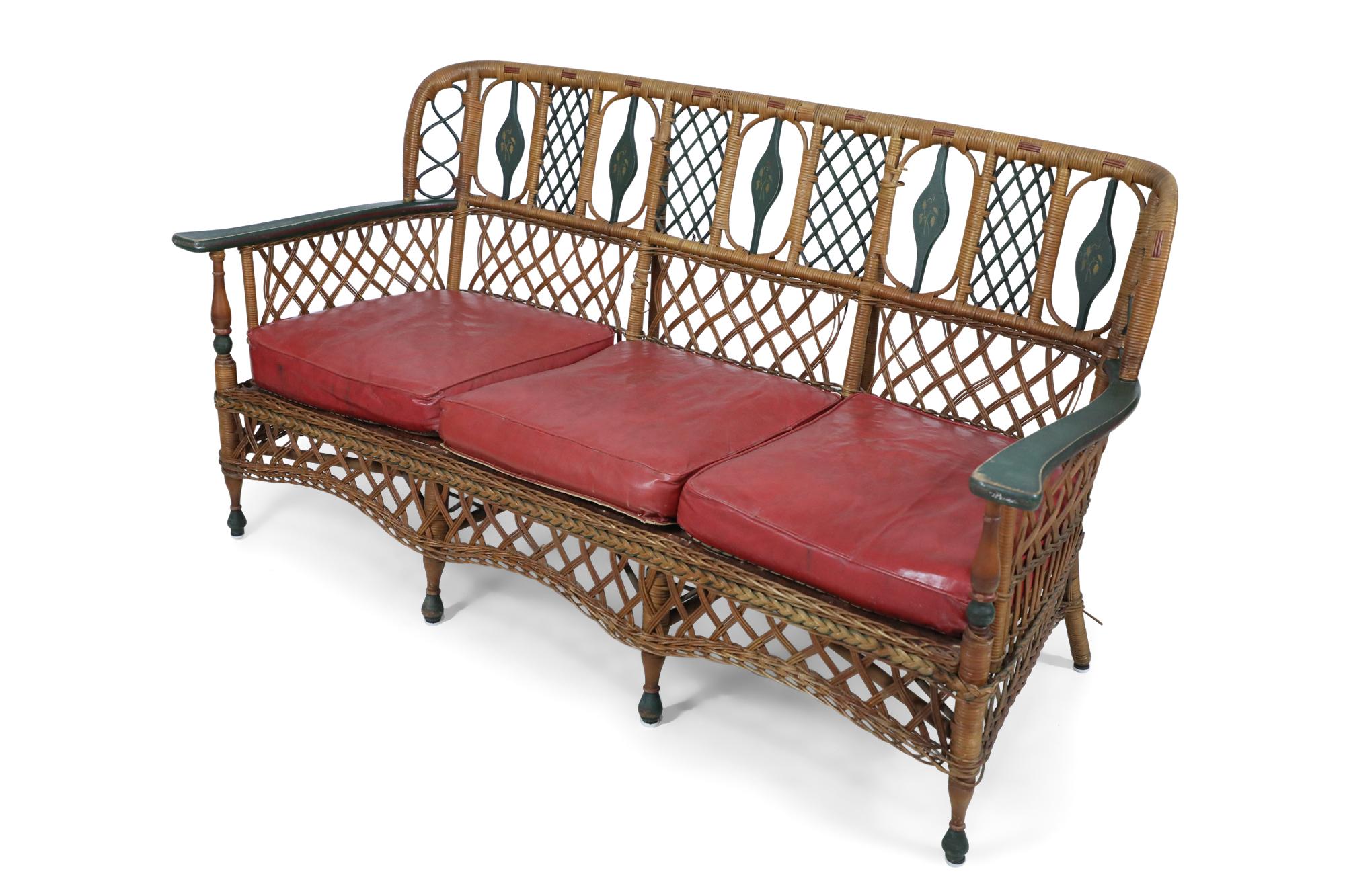 7 piece American Art Deco natural wicker porch / living room set, composed of a filigree design 3-seat sofa and 2 matching armchairs have green painted trim, and 2 side chairs all with red vinyl cushions; match the red & green painted bookshelf and