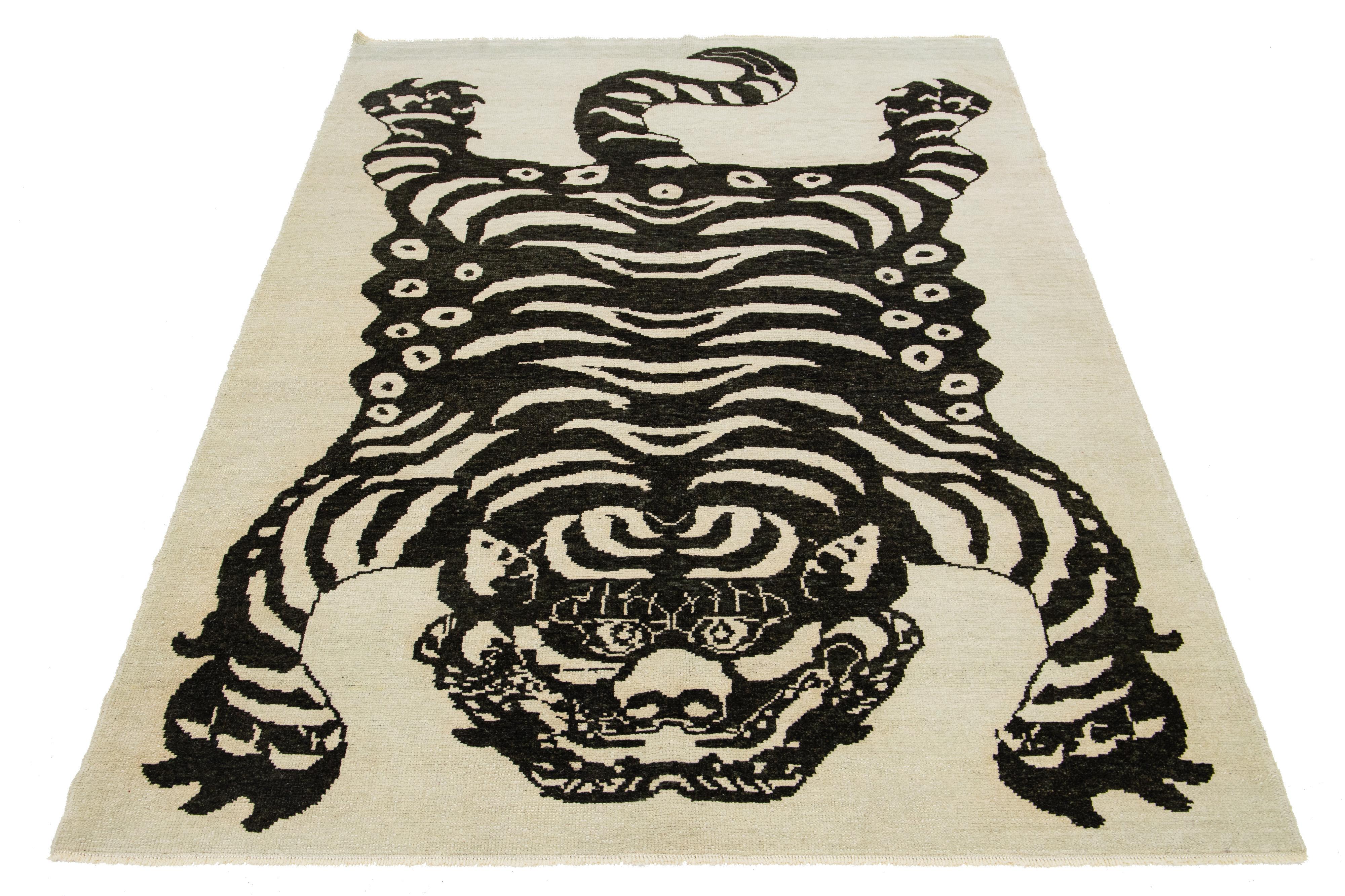 Esta alfombra turca de lana Art Decó presenta un llamativo fondo beige con atrevidos acentos negros y una cautivadora representación pictórica de un tigre.

Esta alfombra mide 1,80 m x 1,80 m. 

