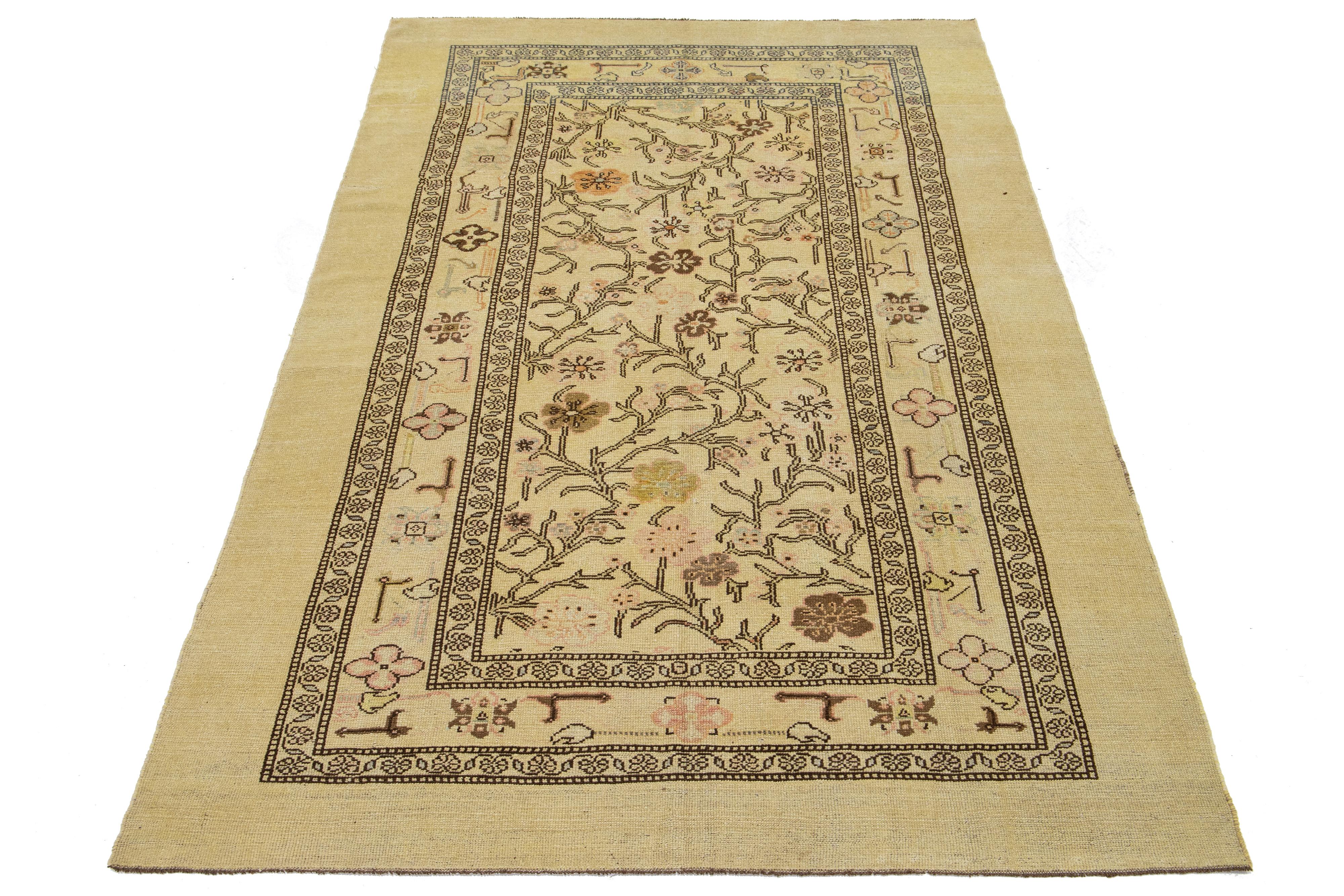 Ein schöner moderner handgeknüpfter Wollteppich mit hellbraunem Hintergrund. Dieser Teppich aus der Apadana Revival Collection'S zeichnet sich durch ein auffälliges geometrisches und botanisches Blumenmuster mit Akzenten in Pfirsich, Braun und