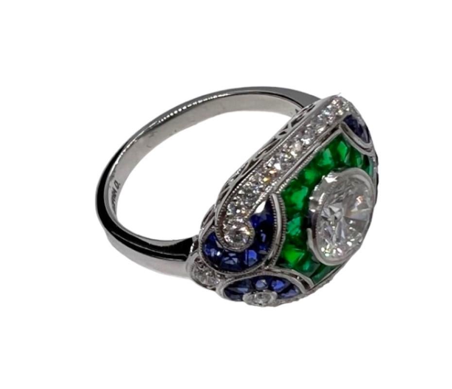 Designed and created by Sophia D, this art deco ring features a 0.70 carat round diamond center surrounded with blue sapphires and emerald that weigh a total of .50 carats.

Sophia D by Joseph Dardashti LTD has been known worldwide for 35 years and