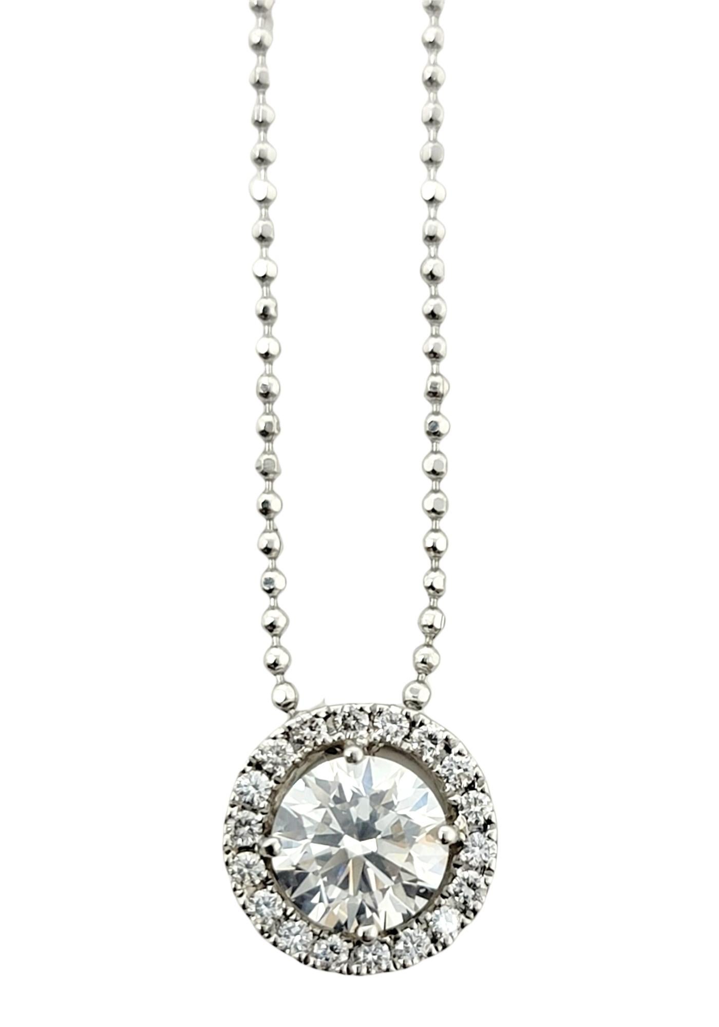 This sparkling diamond halo pendant necklace is stunningly simple, yet undeniably beautiful. The delicate ball chain and icy circle of natural round diamonds goes with just about everything. It features a single round brilliant diamond prong set at