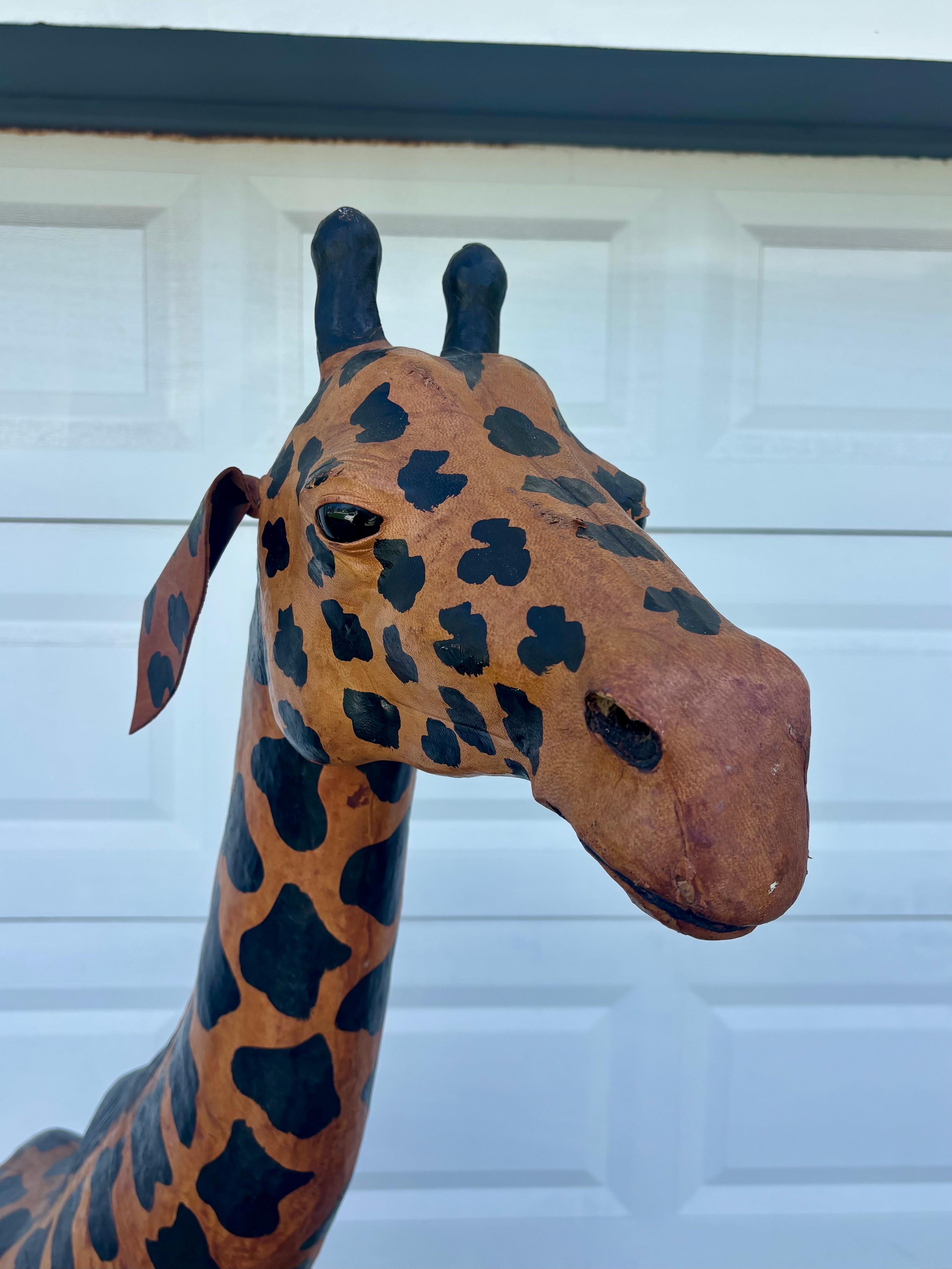 Une étonnante sculpture de girafe de 70,5 pouces de haut, enveloppée de cuir, impressionnante par sa taille et sa présence. Fabriquée avec une forme moulée et enveloppée de cuir peint à la main, cette pièce apporte un charme vintage chaleureux,