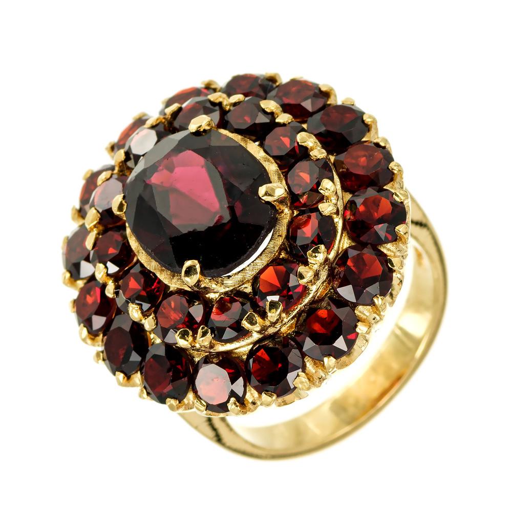 1960's estate garnet cluster cocktail ring. 3.60ct oval brownish red garnet center stone in an 18k yellow gold cluster setting with 2 halos of 28 round garnets totaling 3.40cts. Minor surface abrasions.

1 oval brownish red garnet, approx.