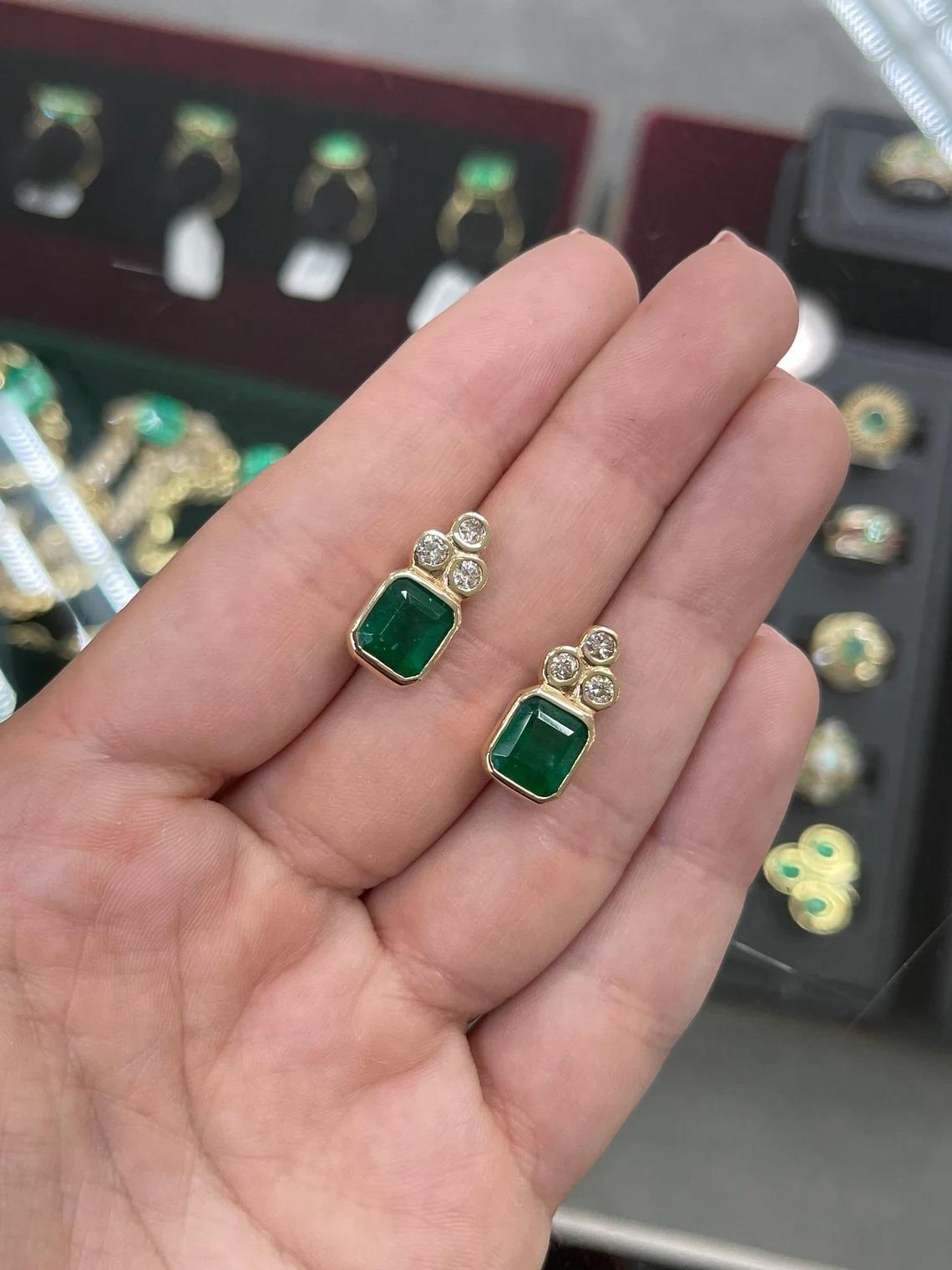 Elegance defined! These large dark rare green emerald and diamond earrings are fashioned in solid hand-made in 14k yellow gold. These studs feature natural emerald cut emeralds accented with natural brilliant white diamonds. The emeralds have a