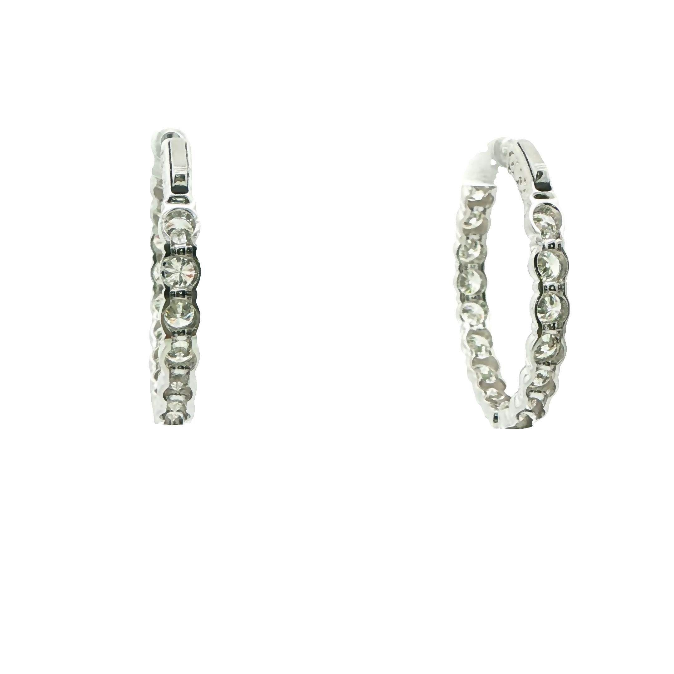 Questi splendidi orecchini a cerchio con diamanti, meticolosamente realizzati in oro bianco 14K con trentasei diamanti tondi brillanti del peso di 7,02 carati di colore H+I e purezza VS2-SI1.