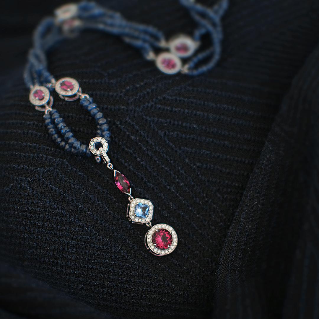 Not only is this necklace absolutely gorgeous, it is also versatile. Blue sapphire beads alternate with rhodolite garnet and diamond cluster sections to form a necklace that can be worn on its own or with the matching enhancer. The enhancer has a