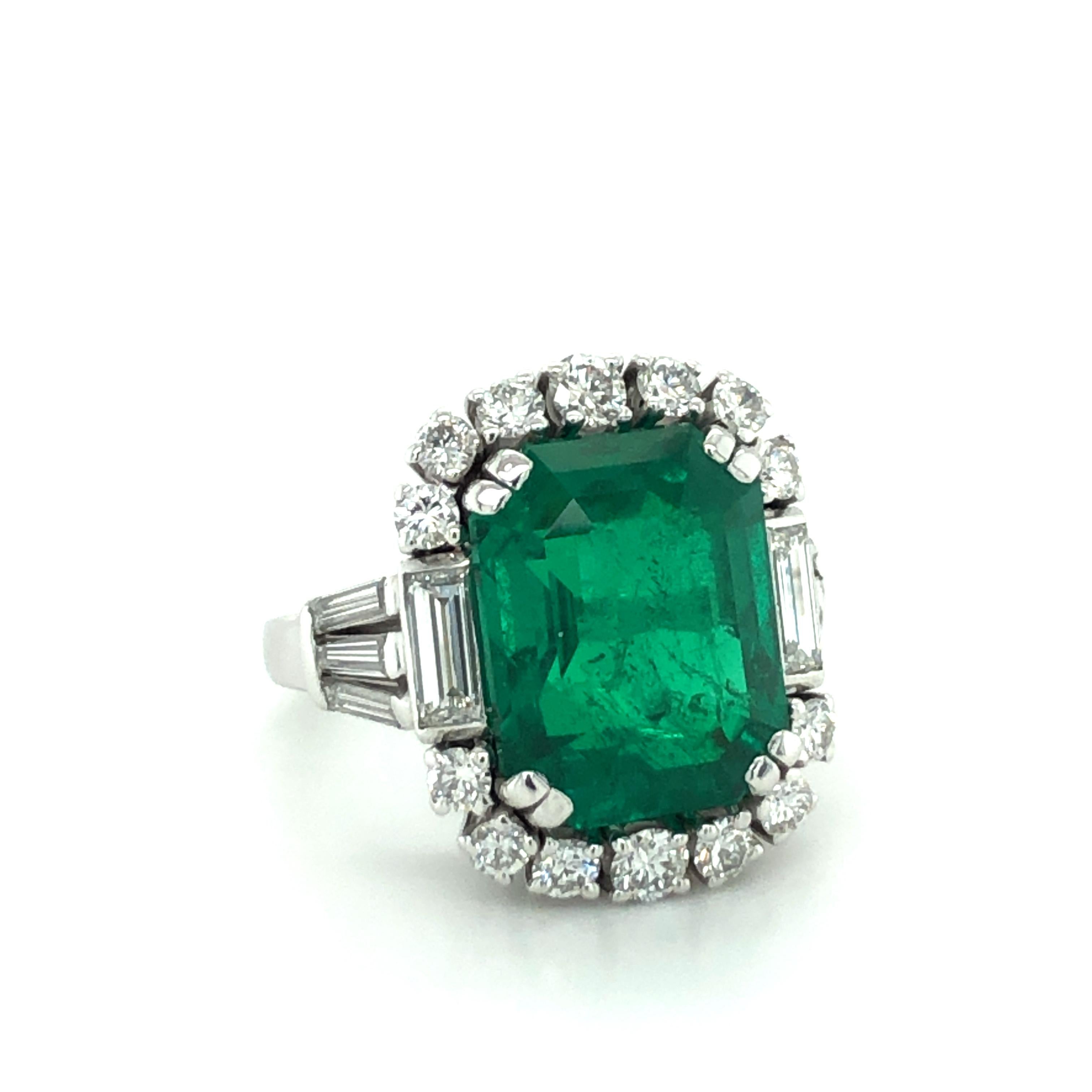 This elegant ring in 18 karat white gold features a stunning octagonal step-cut Colombian emerald of 7.03 carats. The entourage is prong set with 14 brilliant-cut diamonds of F/G colour and vs clarity, total weight approximately 0.60 carats. In