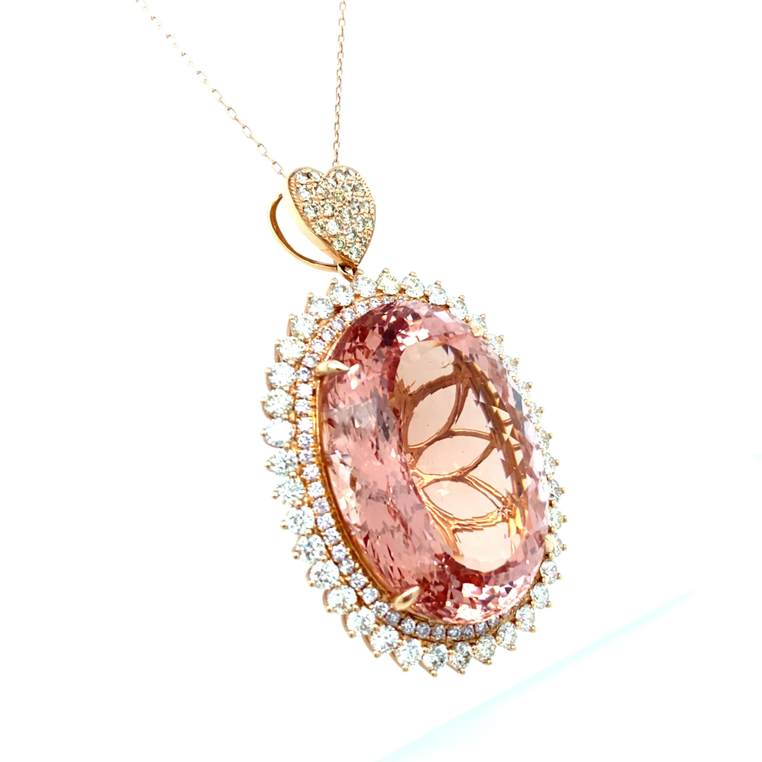 This breathtaking 70.30-carat oval-cut morganite is encircled by a double-row halo of dazzling diamonds. The pendant features a heart-shaped bell design with a beautifully detailed back gallery. Set in 14K rose gold, the necklace has a length of 18