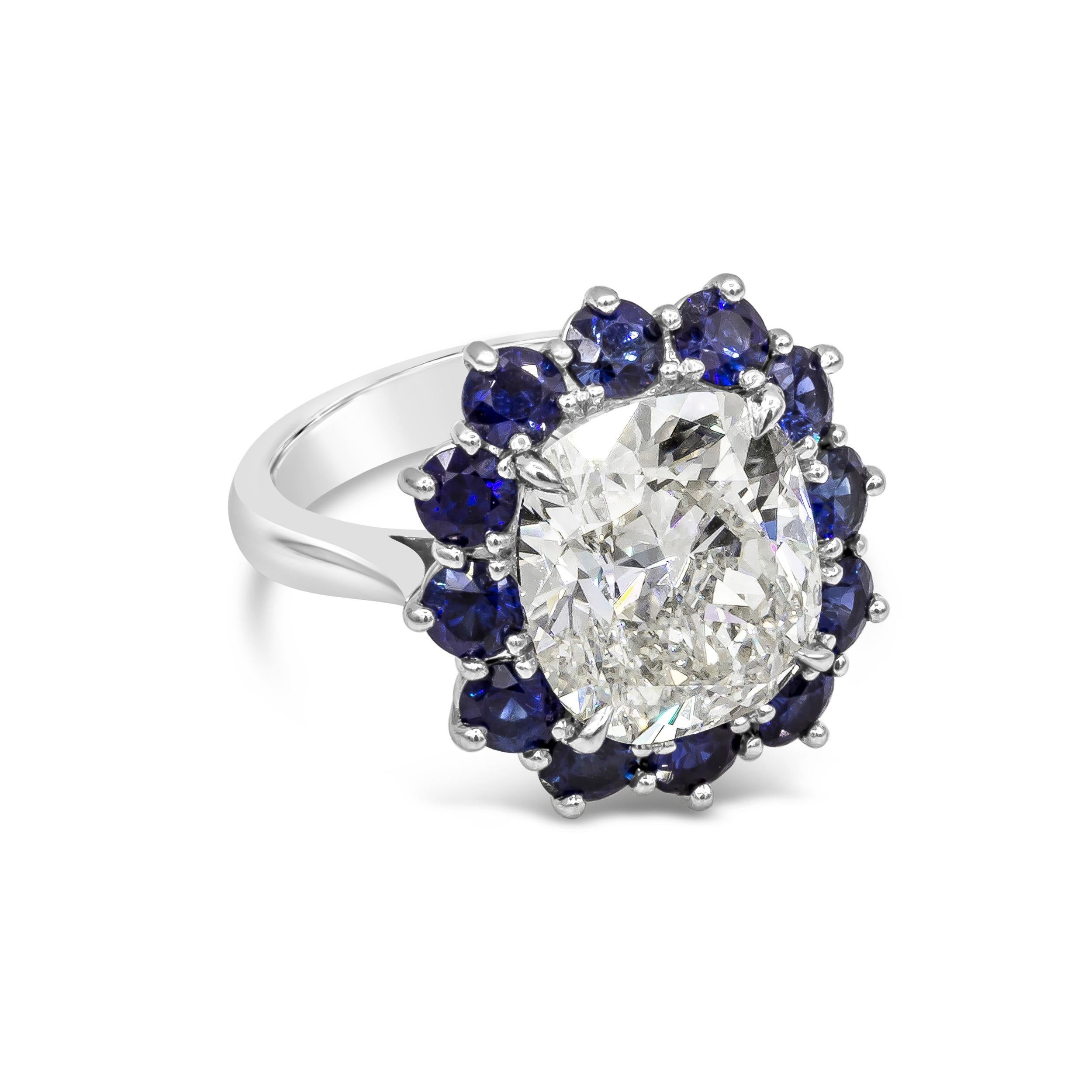 Showcasing a GIA Certified 7.04 carat cushion cut diamond, K Color and SI1 in Clarity. Surrounded by a single row of round cut blue sapphires. Sapphires weigh 2.60 carats total. Made with Platinum. Size 6.25 US 

