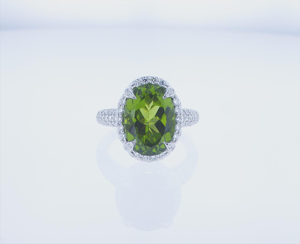 7.05 Carat Oval Peridot cocktail ring in 18k White Gold with Palladium. Featuring 1.37 Carats total weight of G/H color, VS clarity Round Brilliant Diamonds.